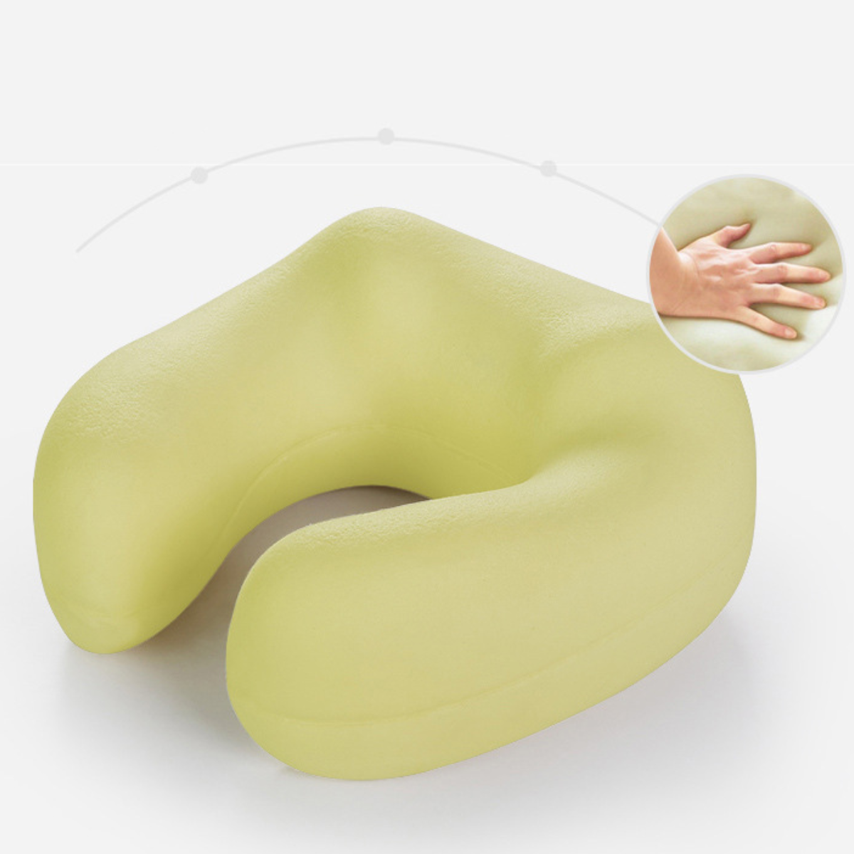 Ein hellgrünes U-förmiges Nackenkissen mit einer Hand, die es drückt. Die Hand ist auf weißem Hintergrund.