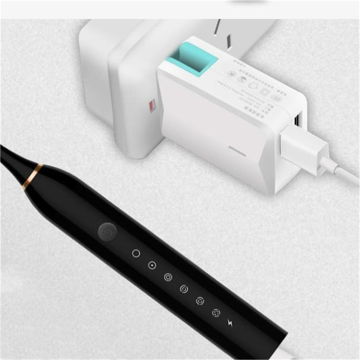 Schwarze elektrische Zahnbürste, die an einen weißen Adapter angeschlossen ist. Weißer Hintergrund.