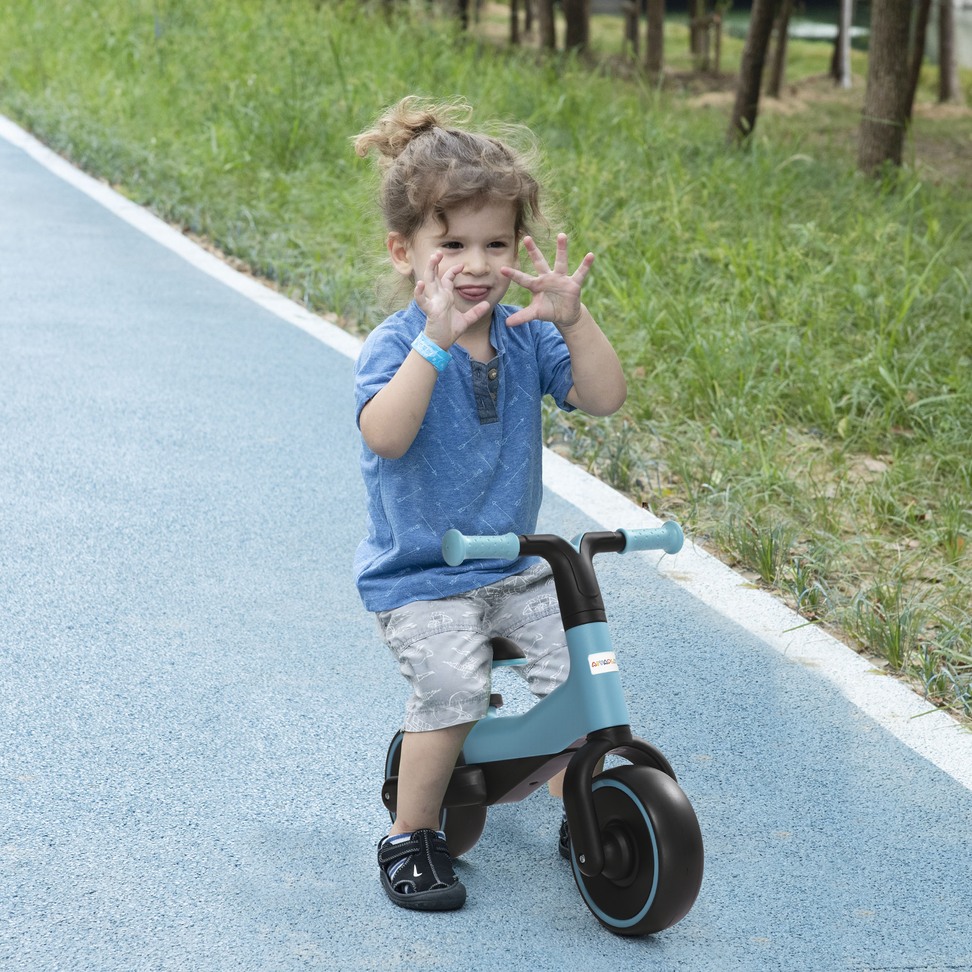 Un niño pequeño en una bicicleta de equilibrio azul en un camino pavimentado.