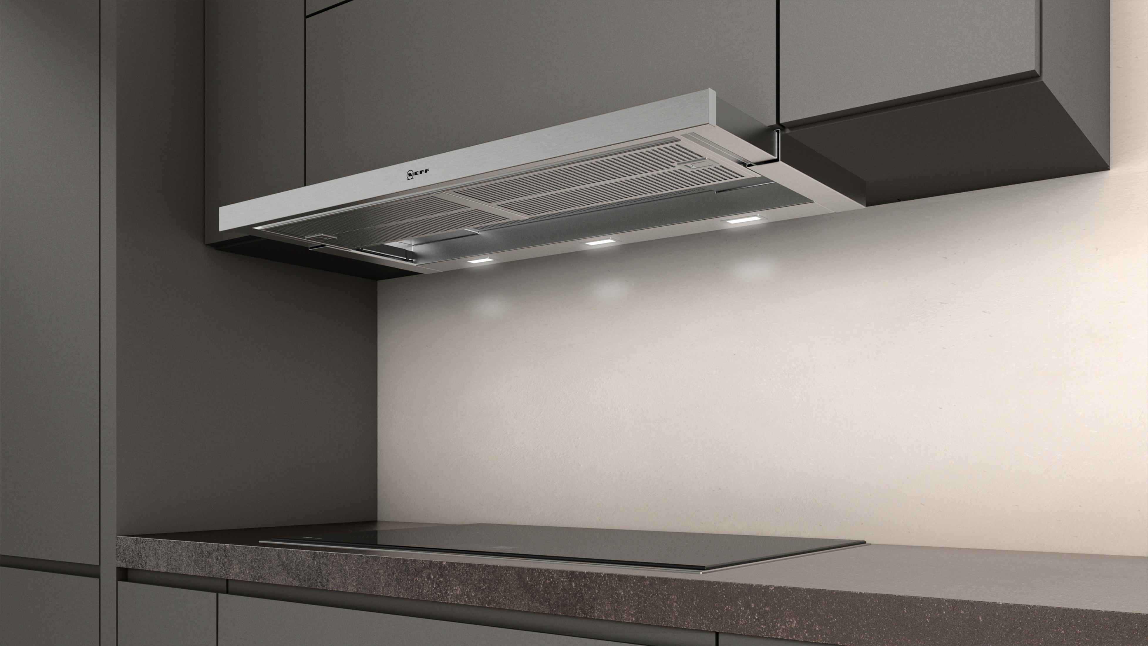 Cappa da cucina installata sopra un piano cottura con sfondo chiaro.