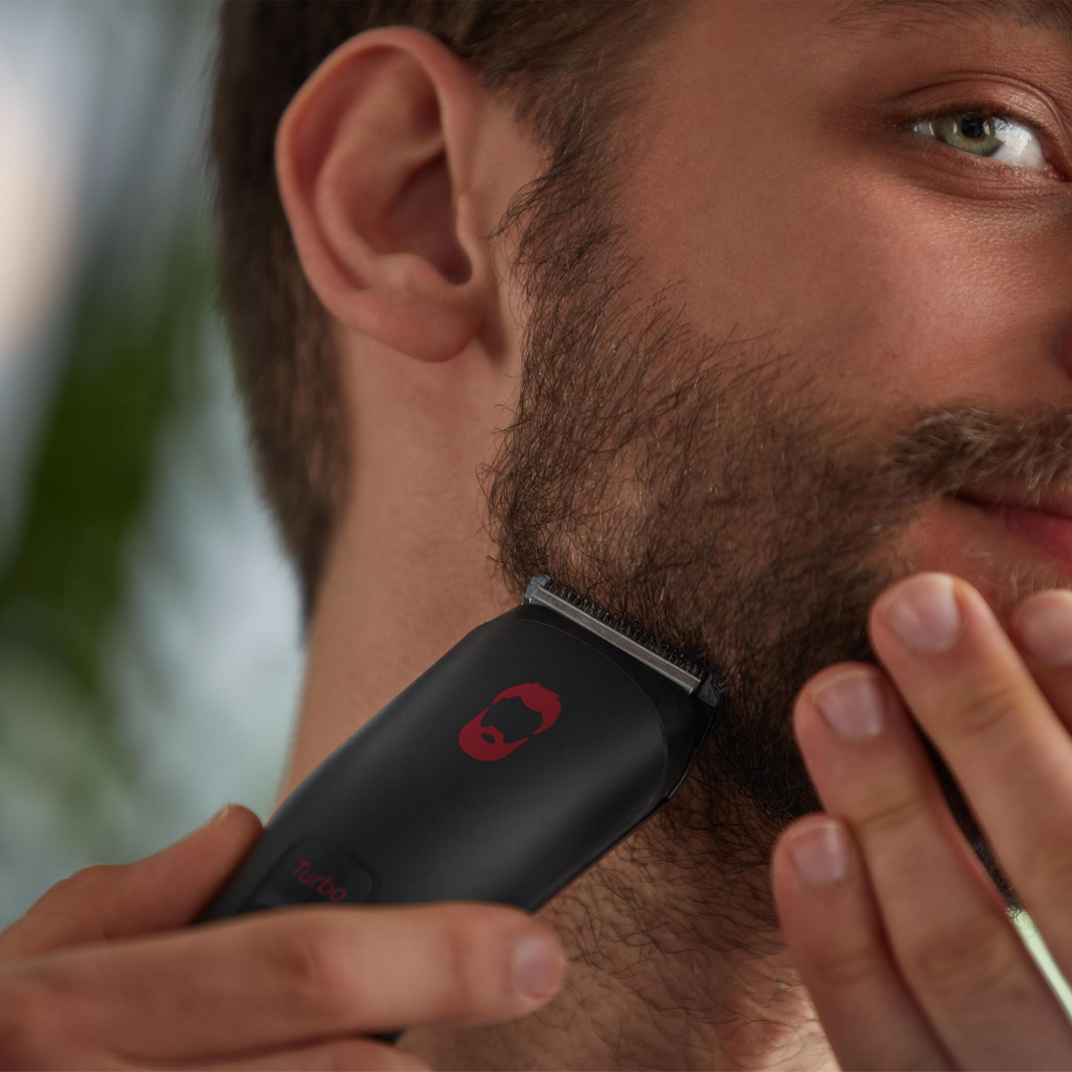 Mann trimmt seinen Bart mit einem schwarzen Trimmer.