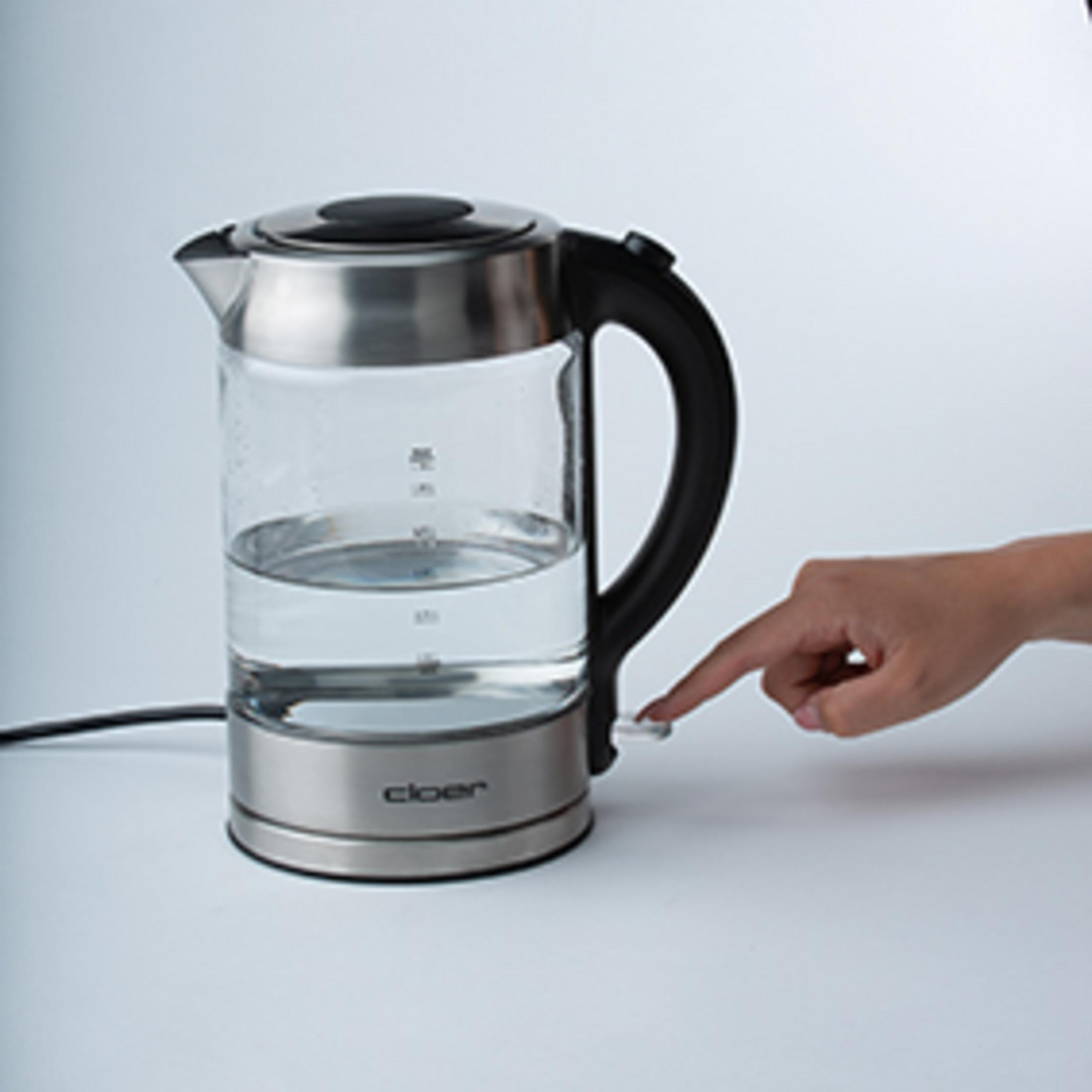 Ręka osoby włączająca czajnik elektryczny z wodą.