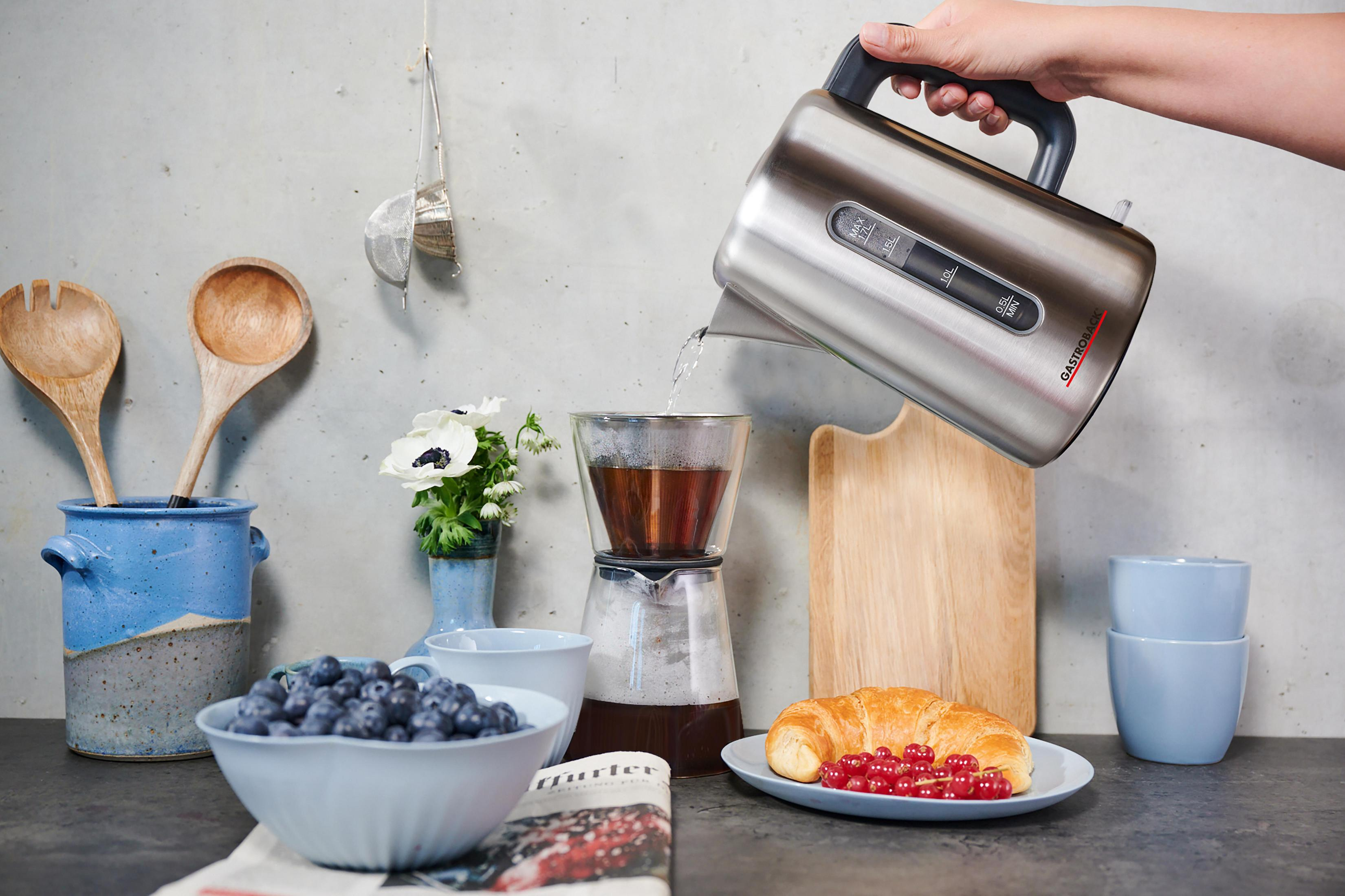 Ręka nalewa wodę z czajnika do szklanego drippera do kawy.