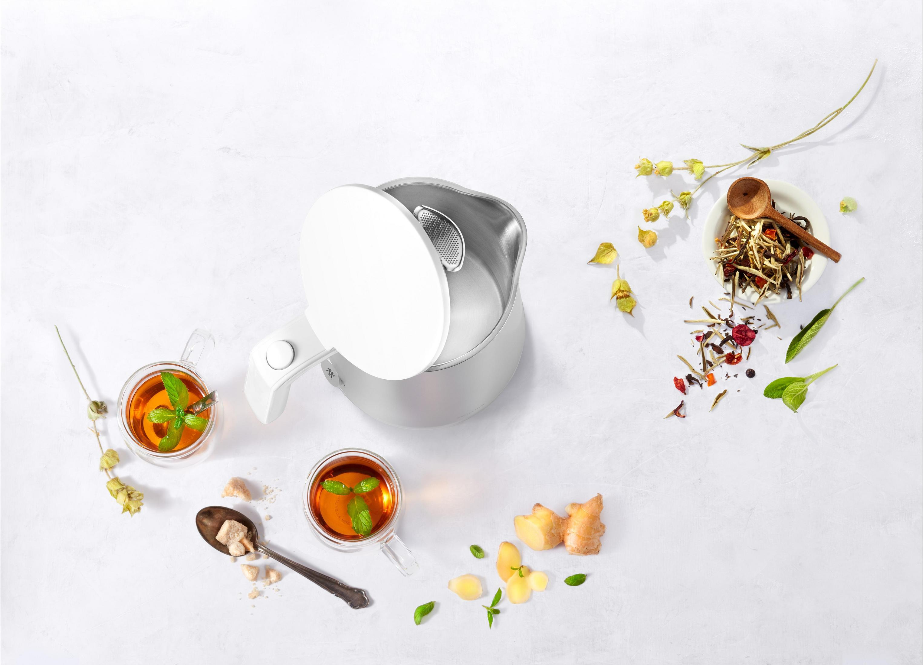 Widok z góry na czajnik i zestaw do herbaty. Dwie filiżanki herbaty, zioła, imbir i łyżka są ułożone.