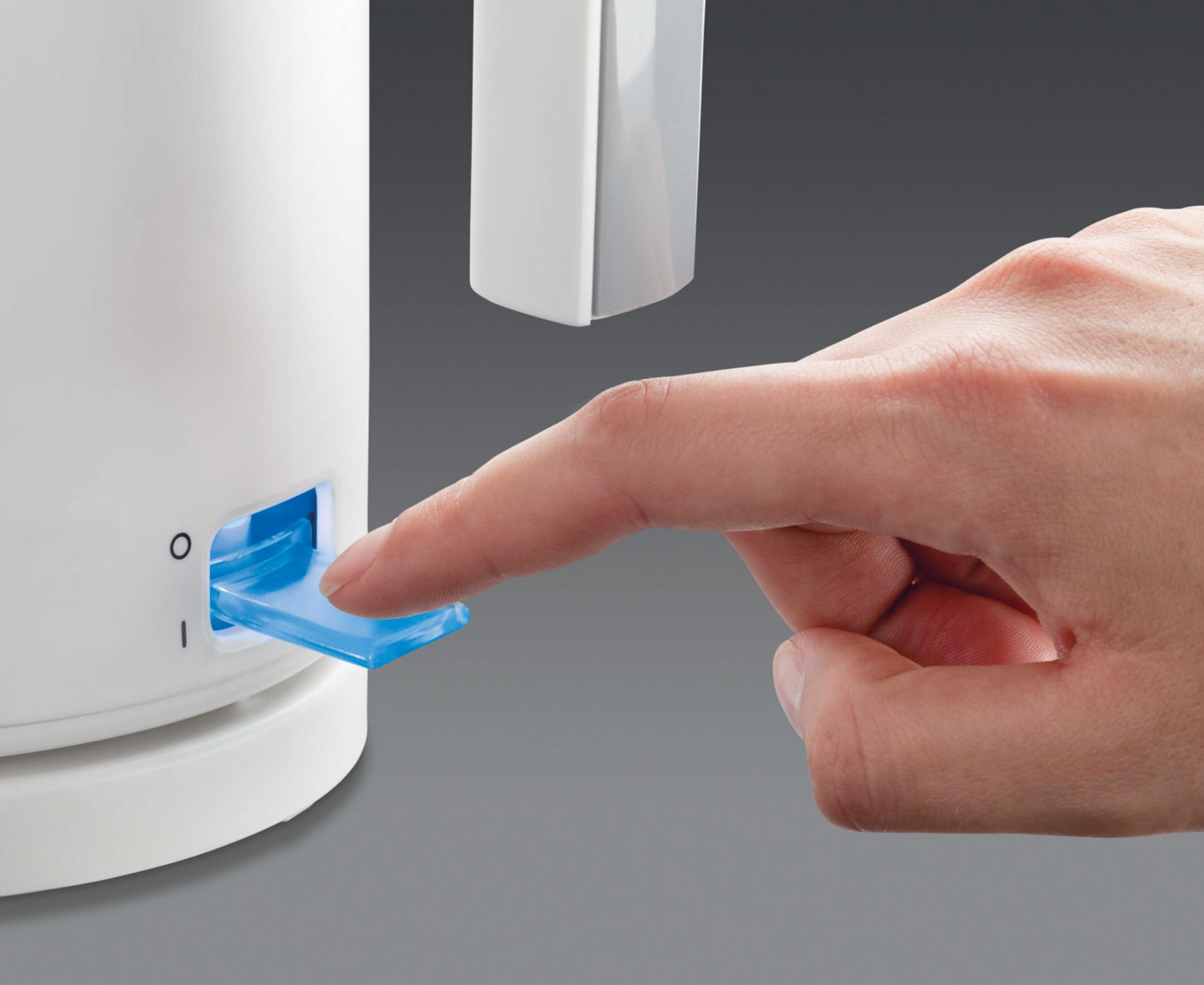 Eine Hand drückt einen blauen Ein-Aus-Schalter an einem weißen Wasserkocher. Der Hintergrund ist grau.