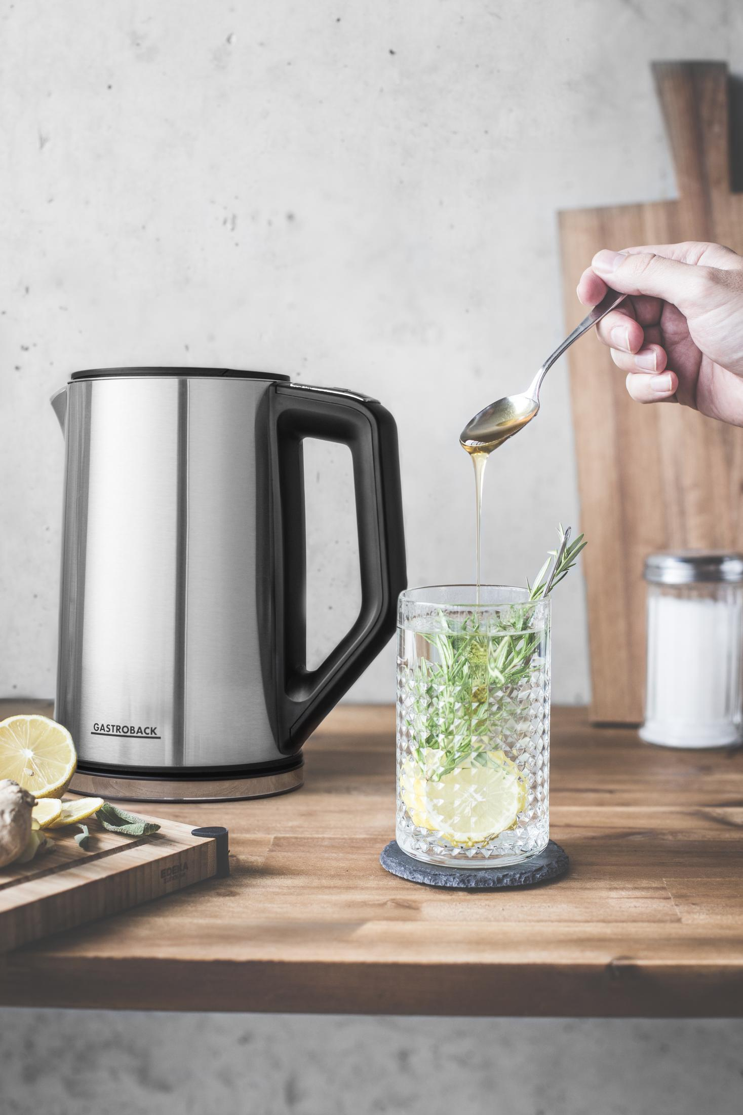 Osoba wlewa miód do szklanki wody z cytryną i rozmarynem.