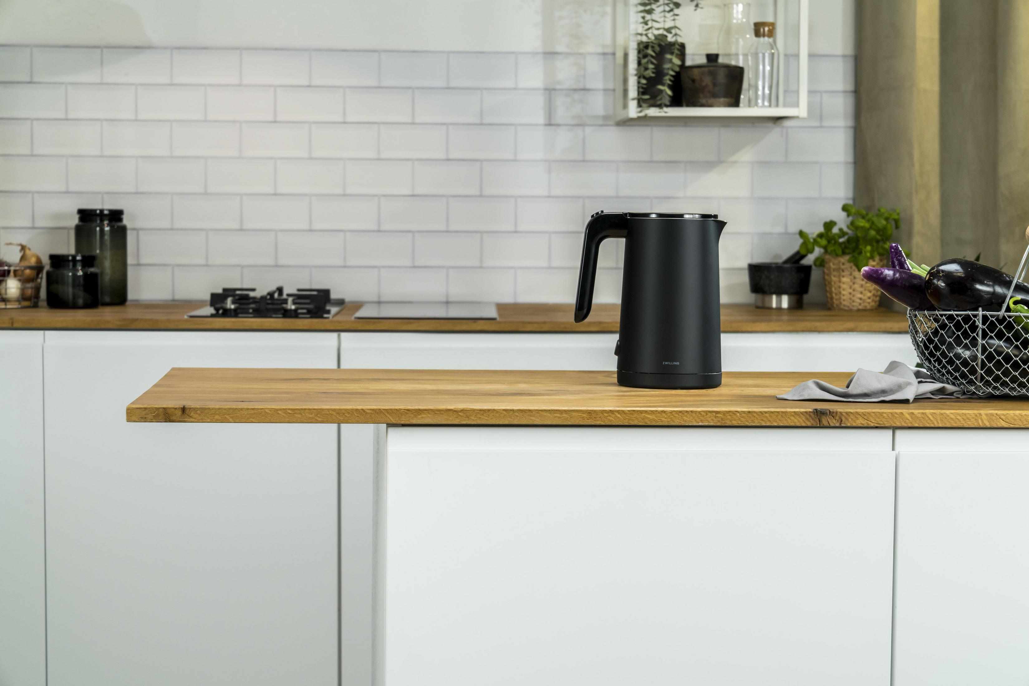 Czarny czajnik elektryczny na drewnianym blacie w kuchni.