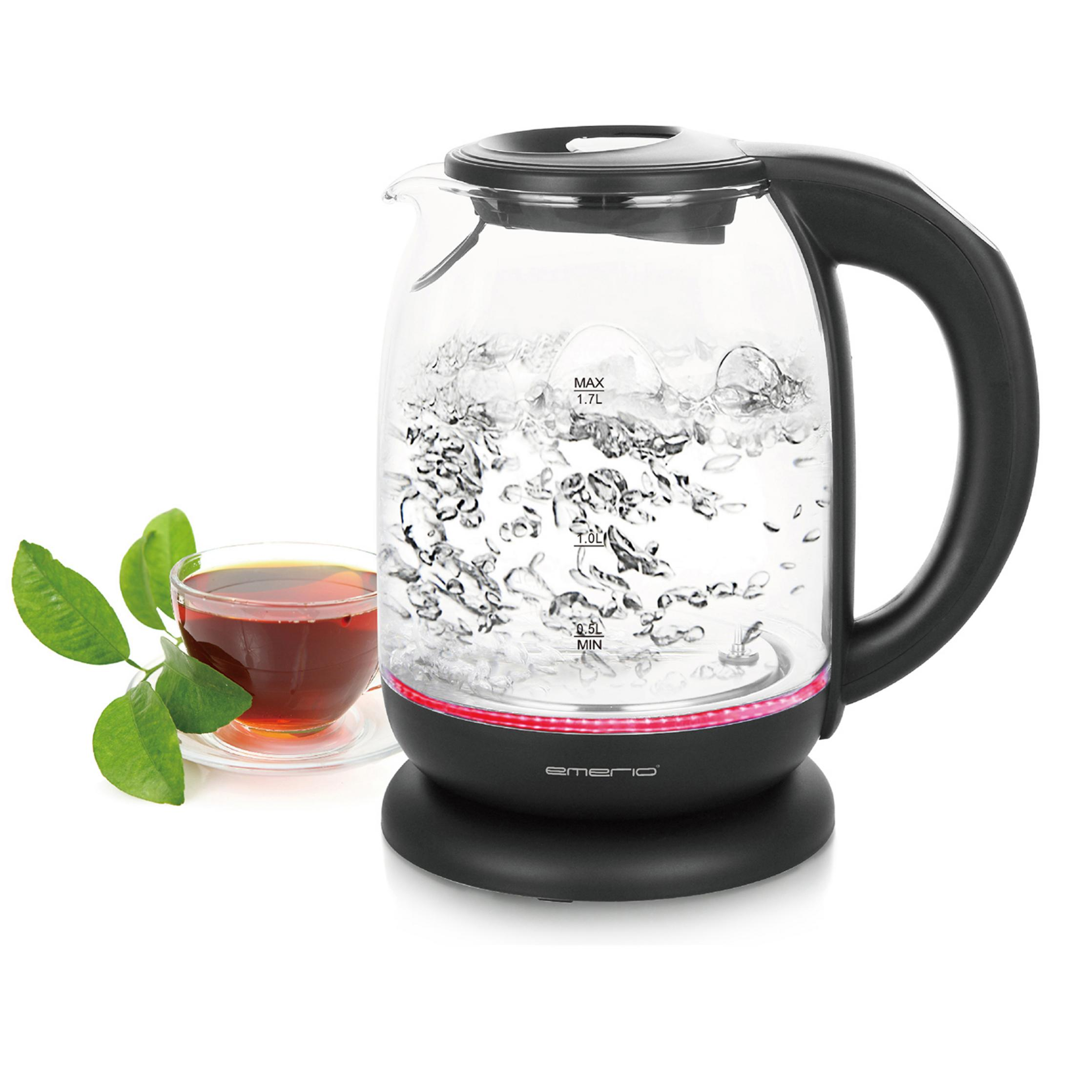 Bollitore elettrico in vetro con acqua bollente, tazza di tè, foglie verdi.
