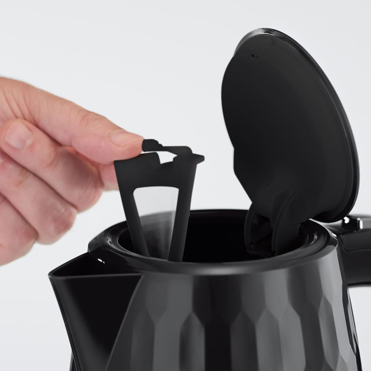 Hand setzt Filter in einen schwarzen elektrischen Wasserkocher ein.