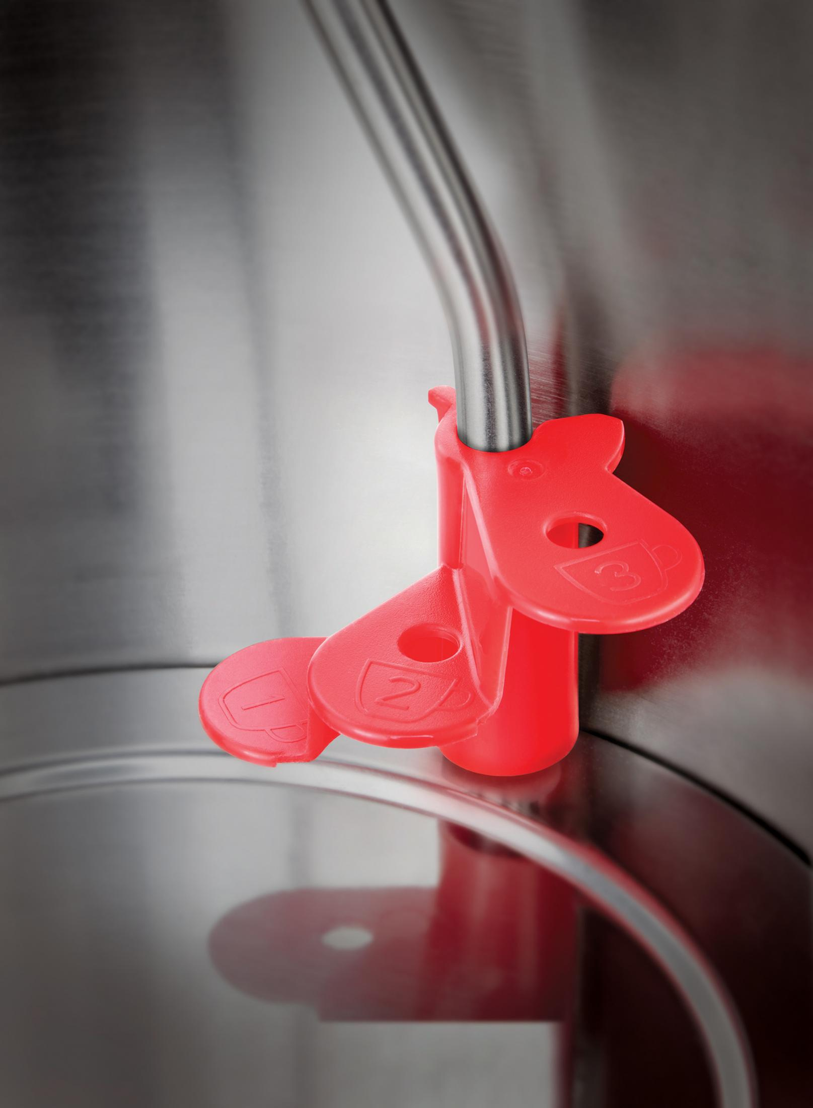 Czerwony plastikowy element wewnątrz srebrnego czajnika ze znacznikami pomiarowymi.