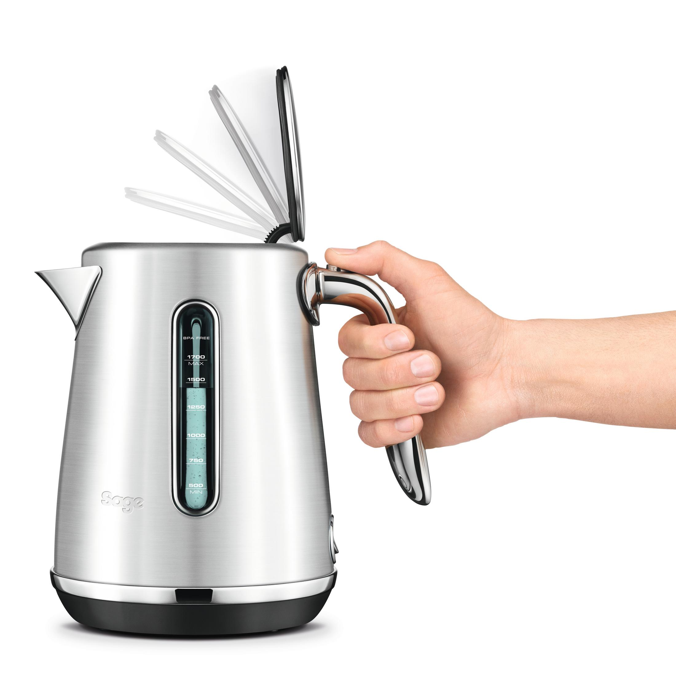 Srebrny czajnik z dłonią otwierającą pokrywę. Pokrywa jest częściowo otwarta.