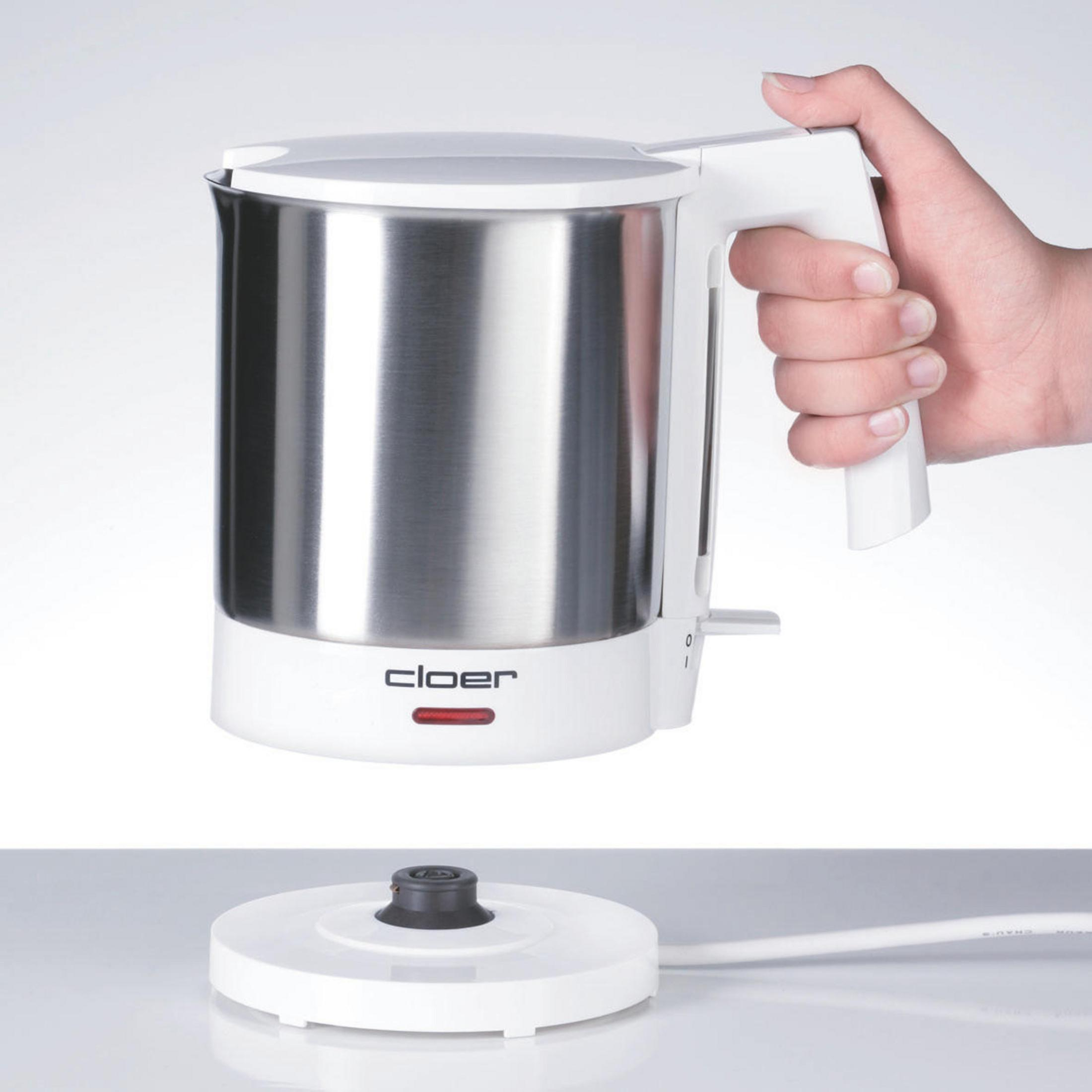 Weißer und silberner elektrischer Wasserkocher mit weißem Sockel und einer Hand am Griff.