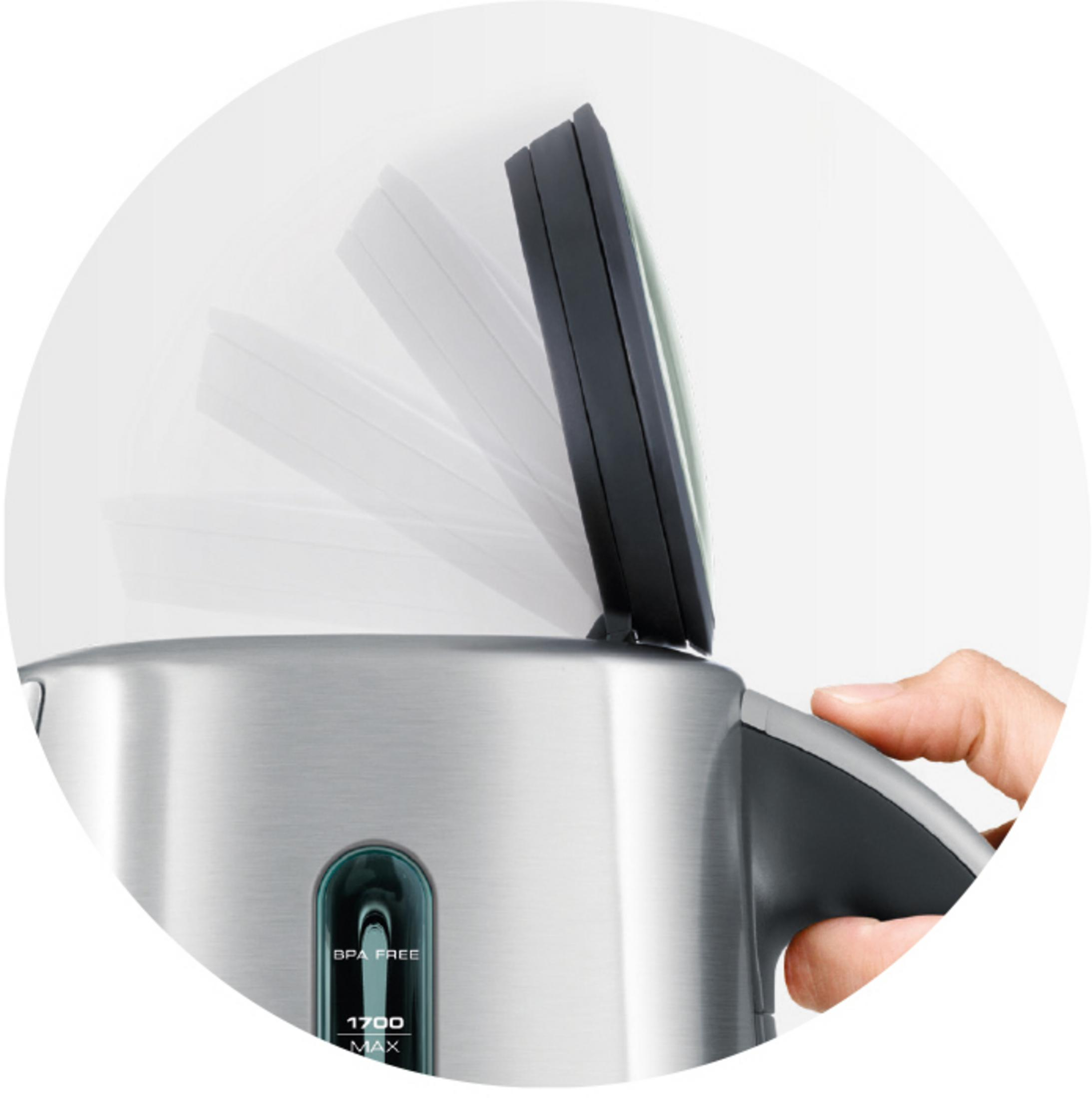 Ręka otwiera pokrywę srebrnego czajnika. Pokrywa jest czarna.