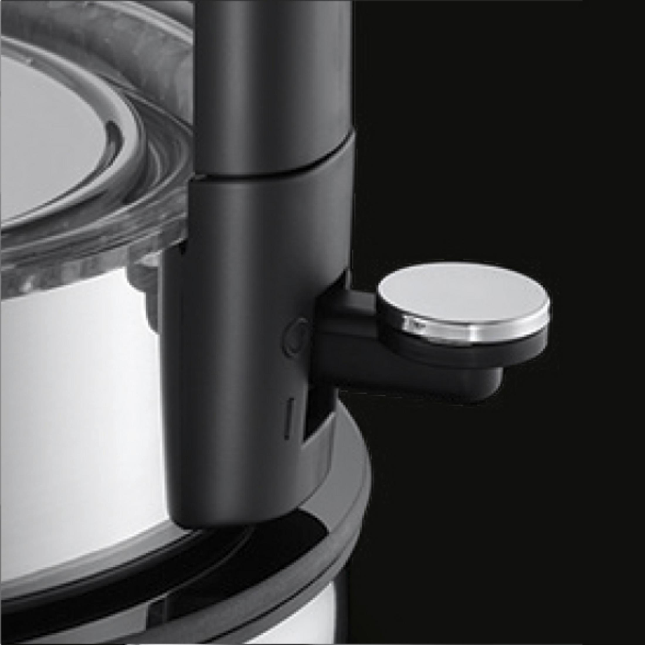 Nahaufnahme eines Küchengeräts mit schwarzem Griff und metallischem, rundem Knopf.