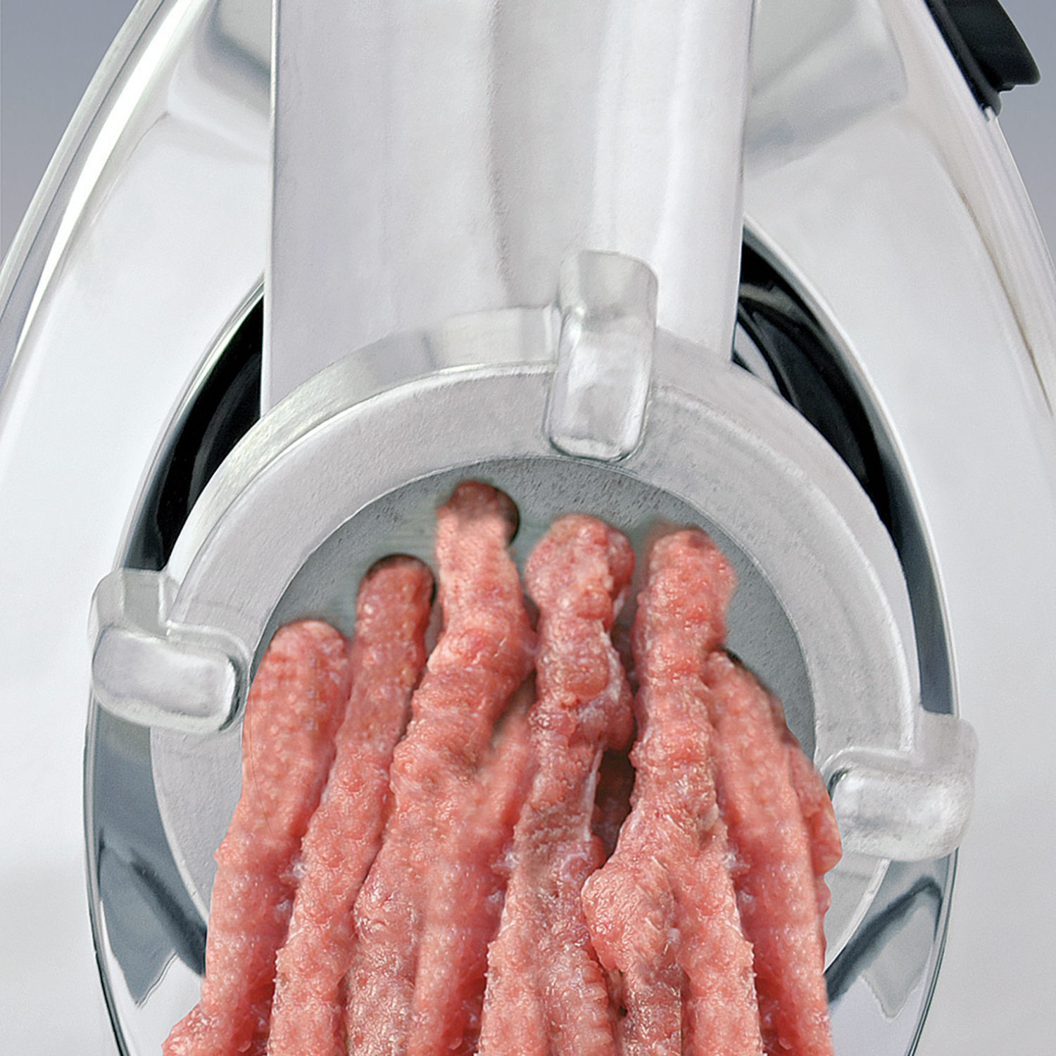Vista de cerca de una picadora de carne con carne picada cruda saliendo.