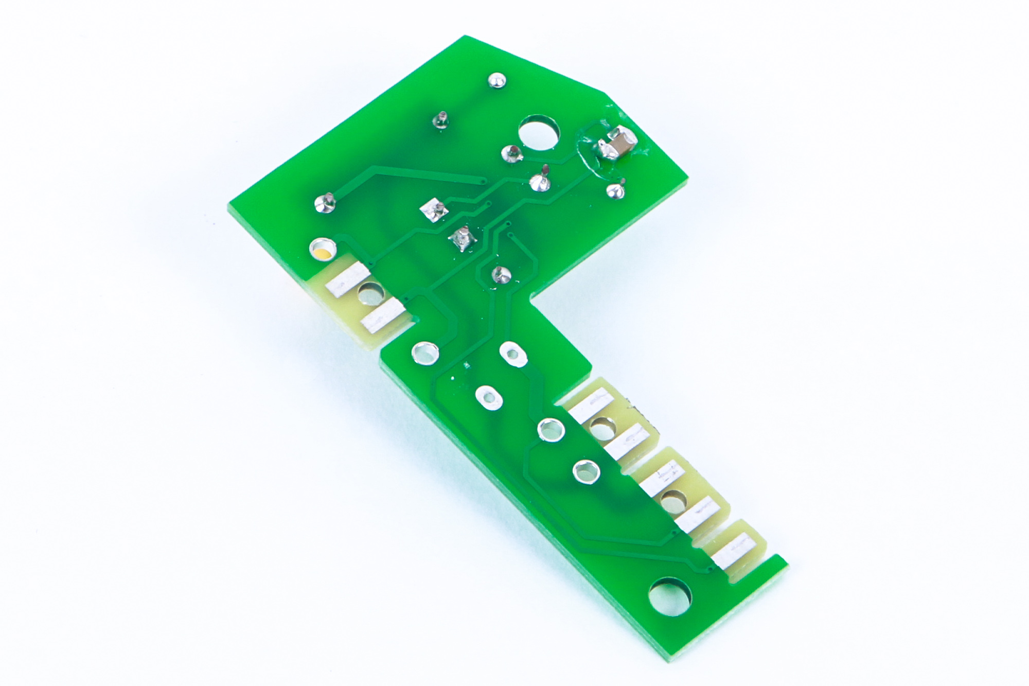 Eine grüne Leiterplatte mit elektronischen Bauteilen und Lötpunkten, auf Weiß.