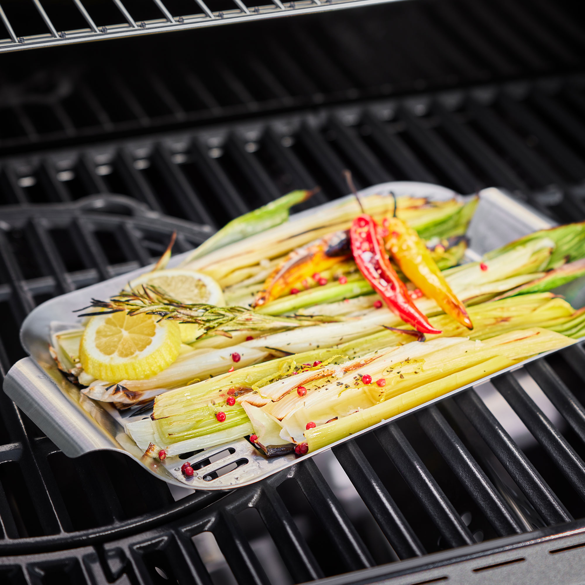 Essen auf dem Grill: Lauch, Zitrone, Rosmarin und rote/gelbe Paprika in einer Schale.