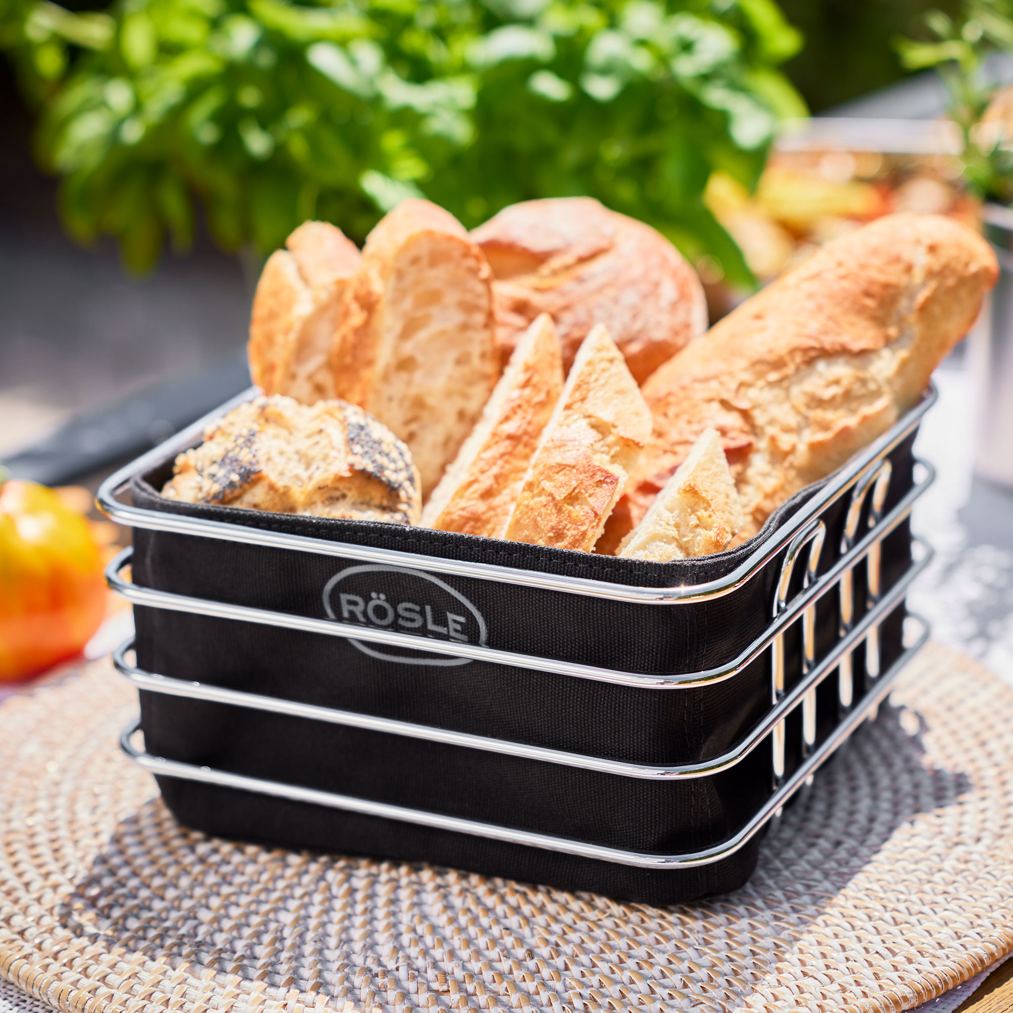 Brotsieb mit verschiedenen Brotscheiben, Rösle-Logo. Korb steht auf geflochtener Matte.