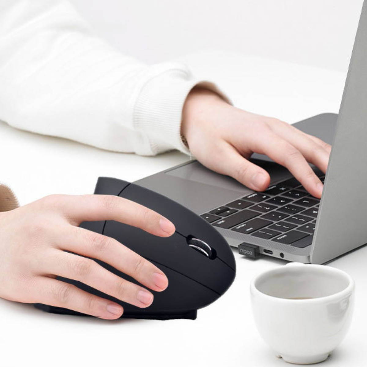 Person benutzt schwarze vertikale Maus mit Laptop, Kaffeetasse.
