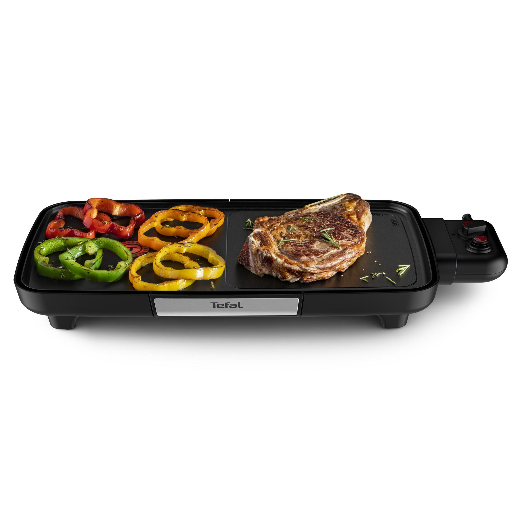 Ein schwarzer Elektrogrill mit gebratenem Steak und Gemüse darauf, auf weißem Hintergrund.