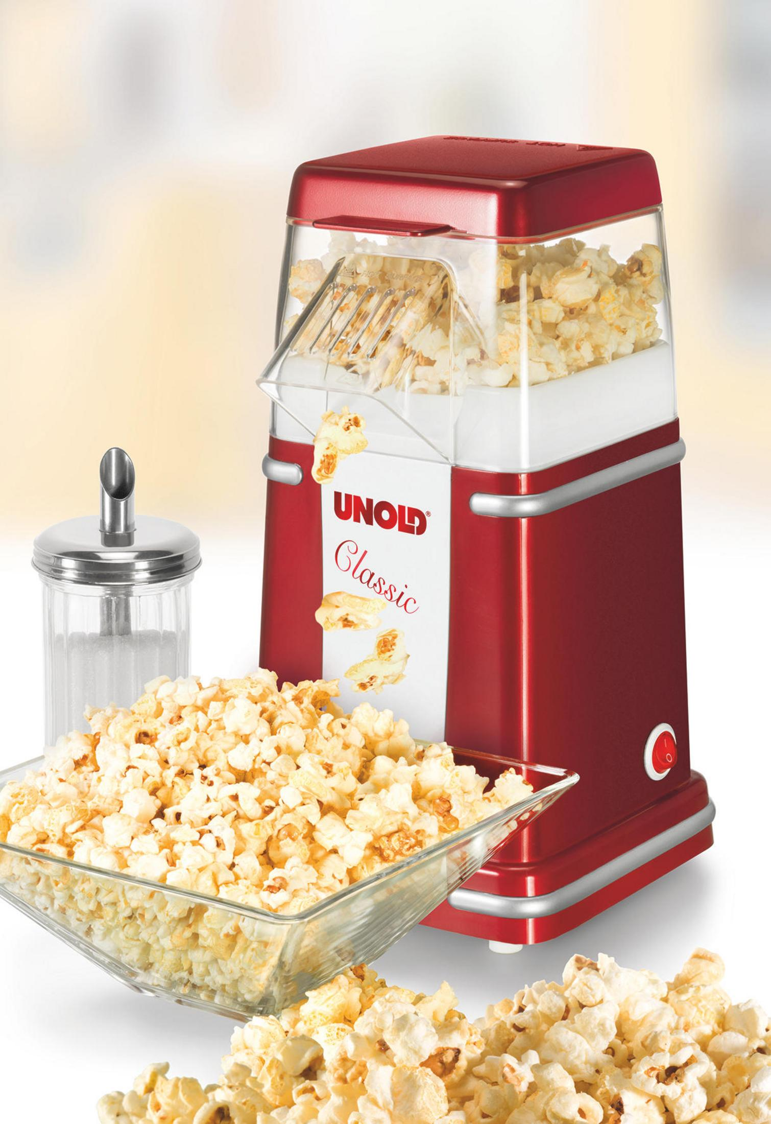 Máquina de palomitas roja con palomitas y un cuenco. Un recipiente de azúcar está a la izquierda.