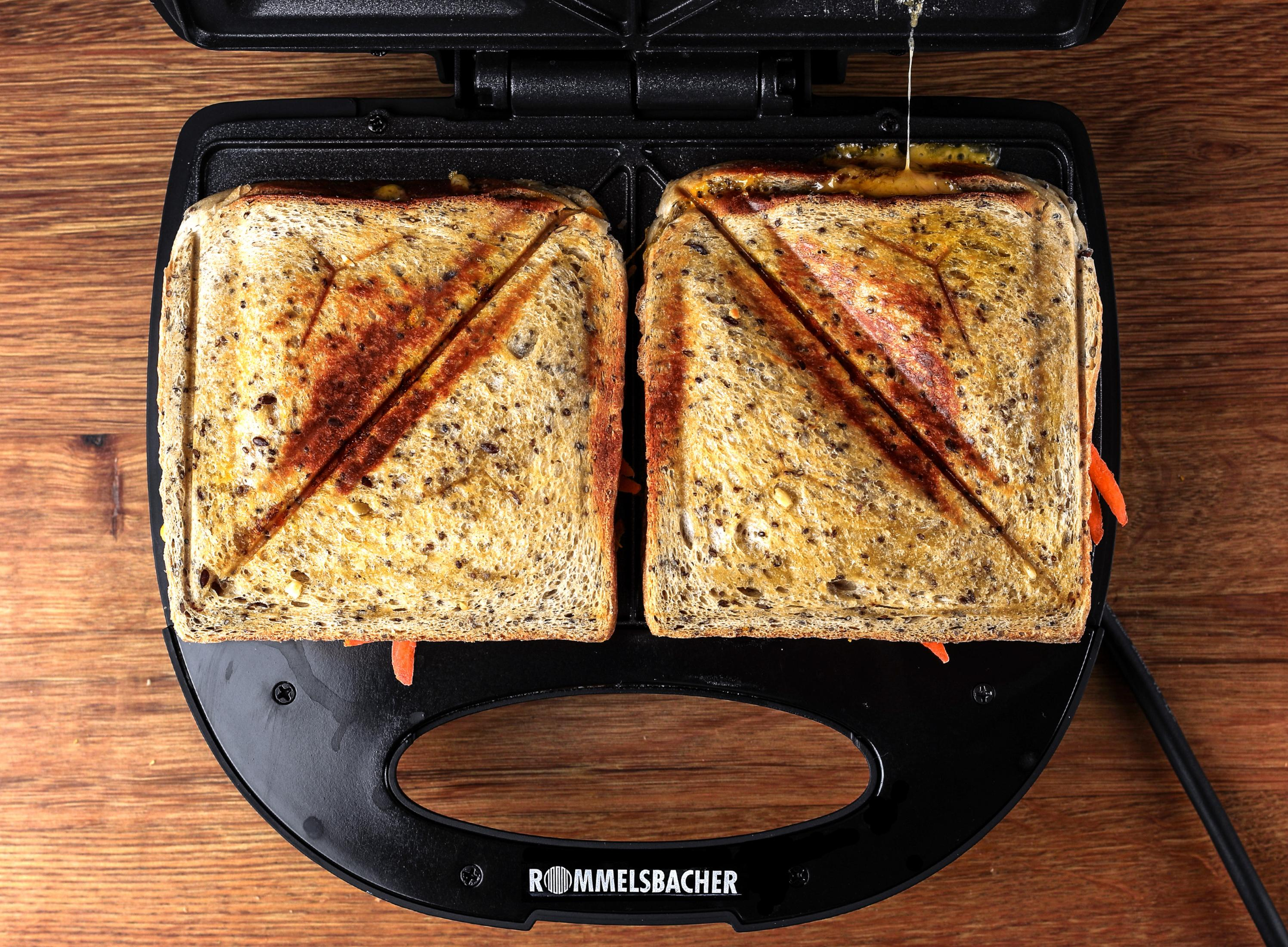 Toster do kanapek z dwiema grillowanymi kanapkami. Kanapki mają znak grilla w kształcie krzyża.