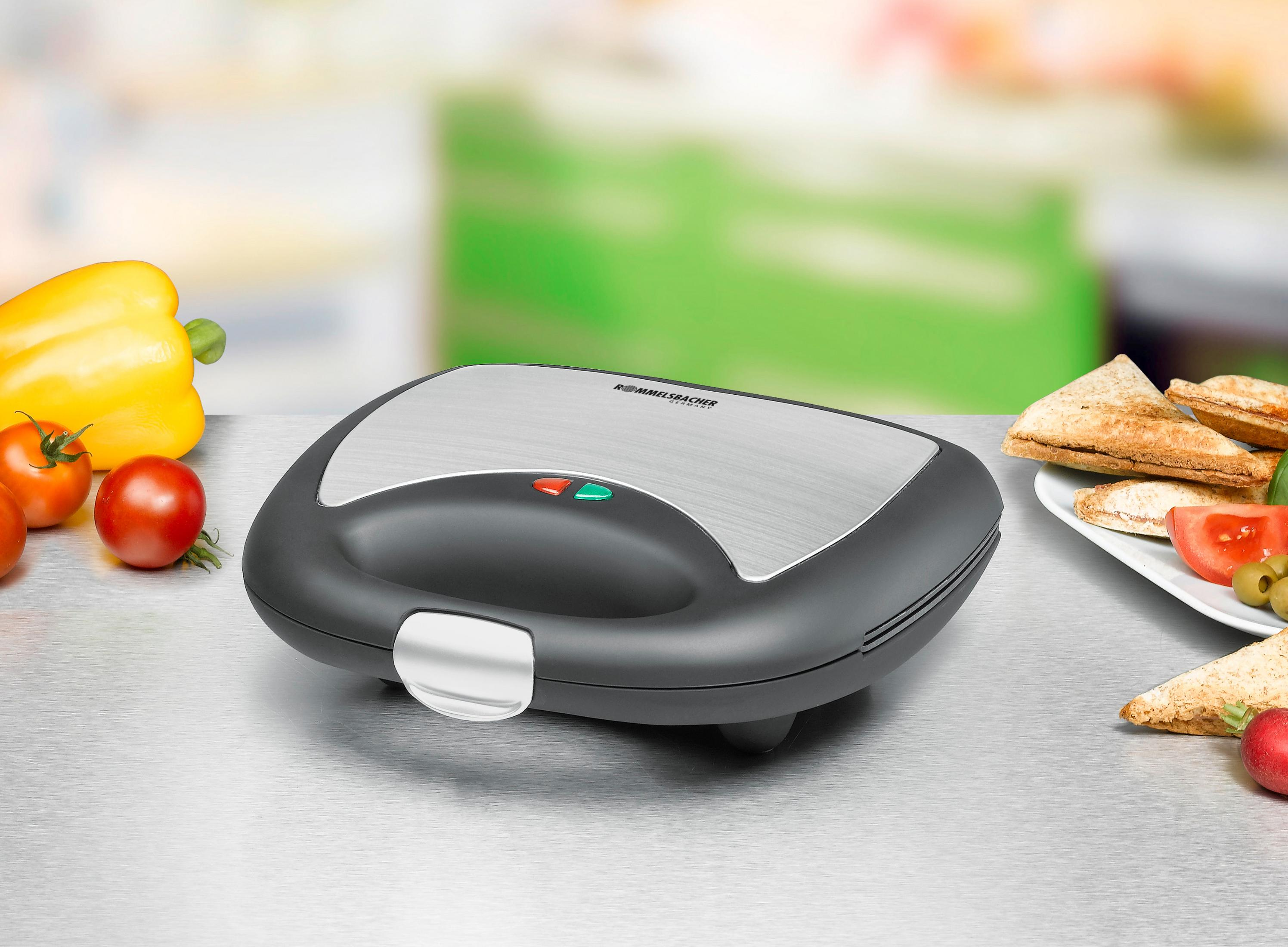 Toster do kanapek z jedzeniem na stole, rozmyte tło kuchni.