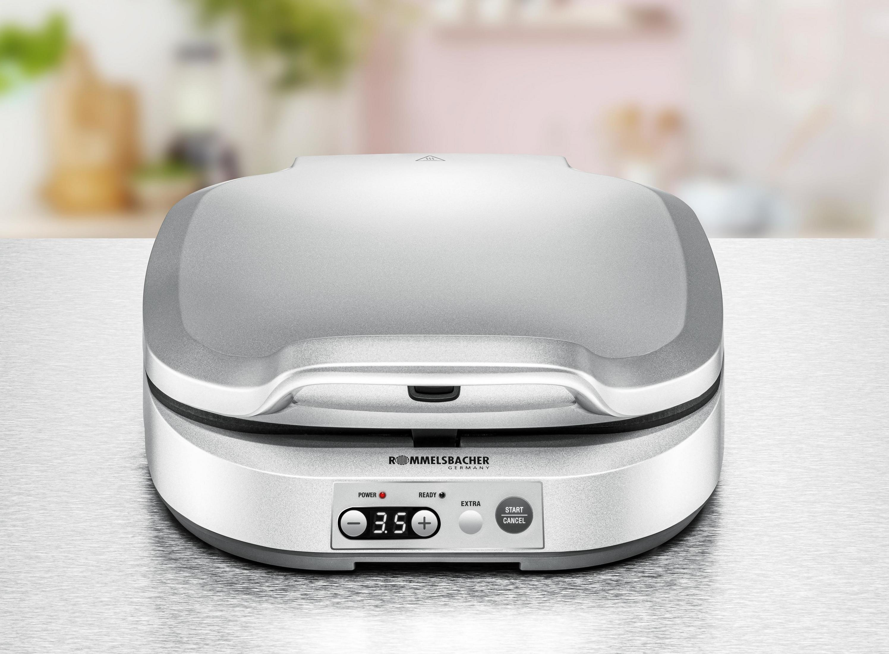 Srebrna gofrownica na jasnej powierzchni. Z przodu znajdują się przyciski i mały wyświetlacz.