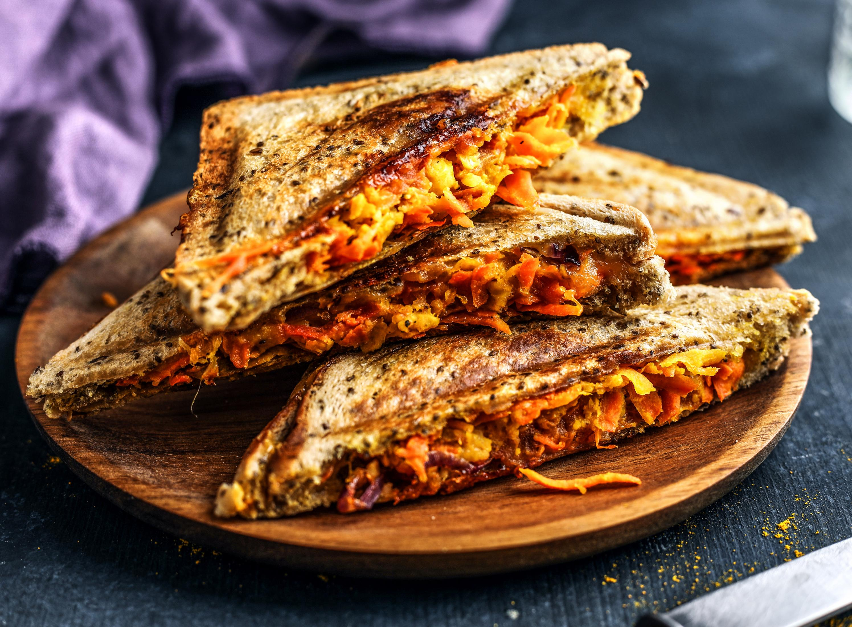 Czarna płyta grzejna z czterema palnikami i drewnianym blatem.