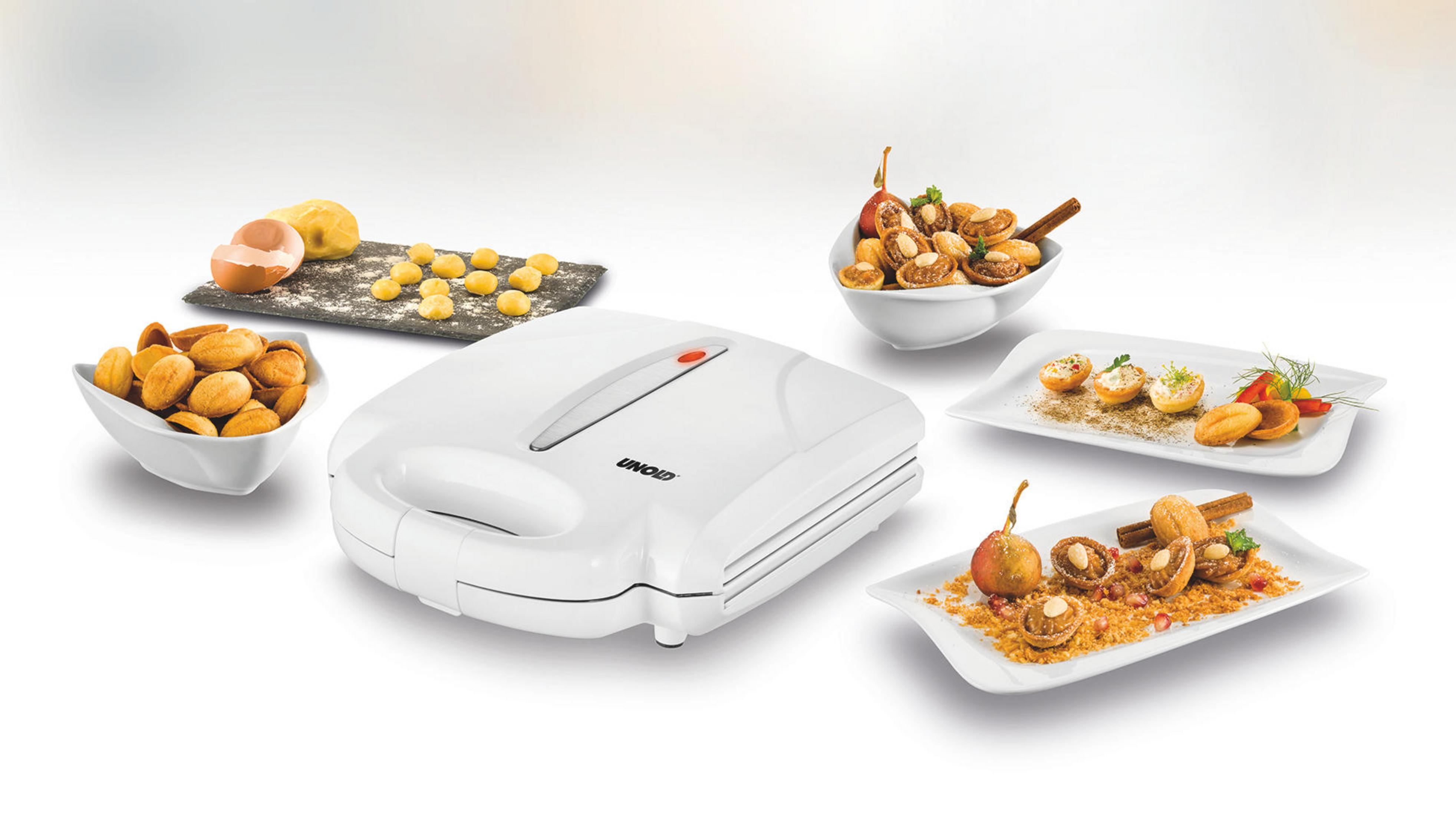 Biała gofrownica z jedzeniem. Zawiera gofry i przygotowane przekąski. Produkty spożywcze są w miskach i na talerzach.