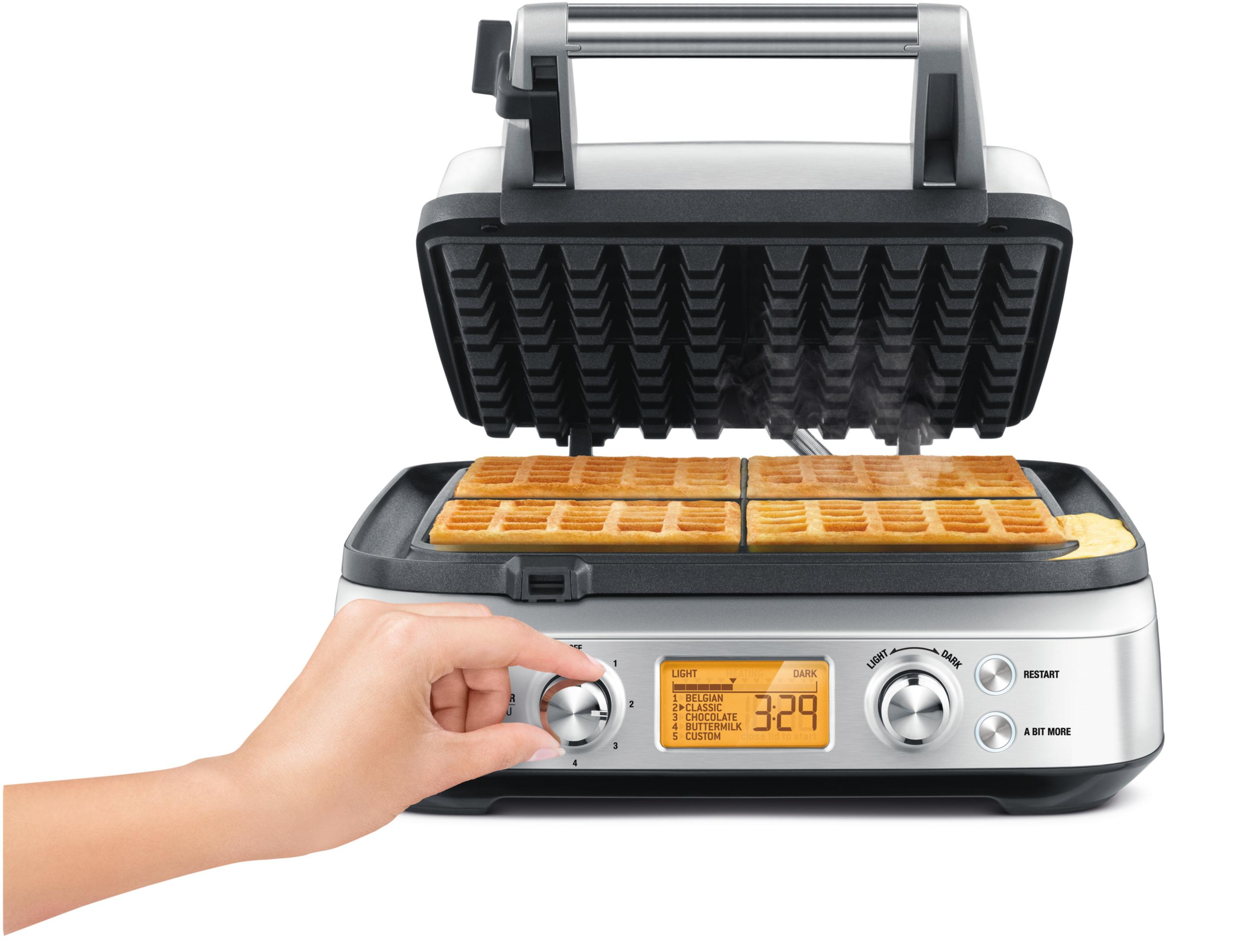 Waffeleisen mit Waffeln darin. Hand stellt Einstellungen ein. Display zeigt Zeit an.