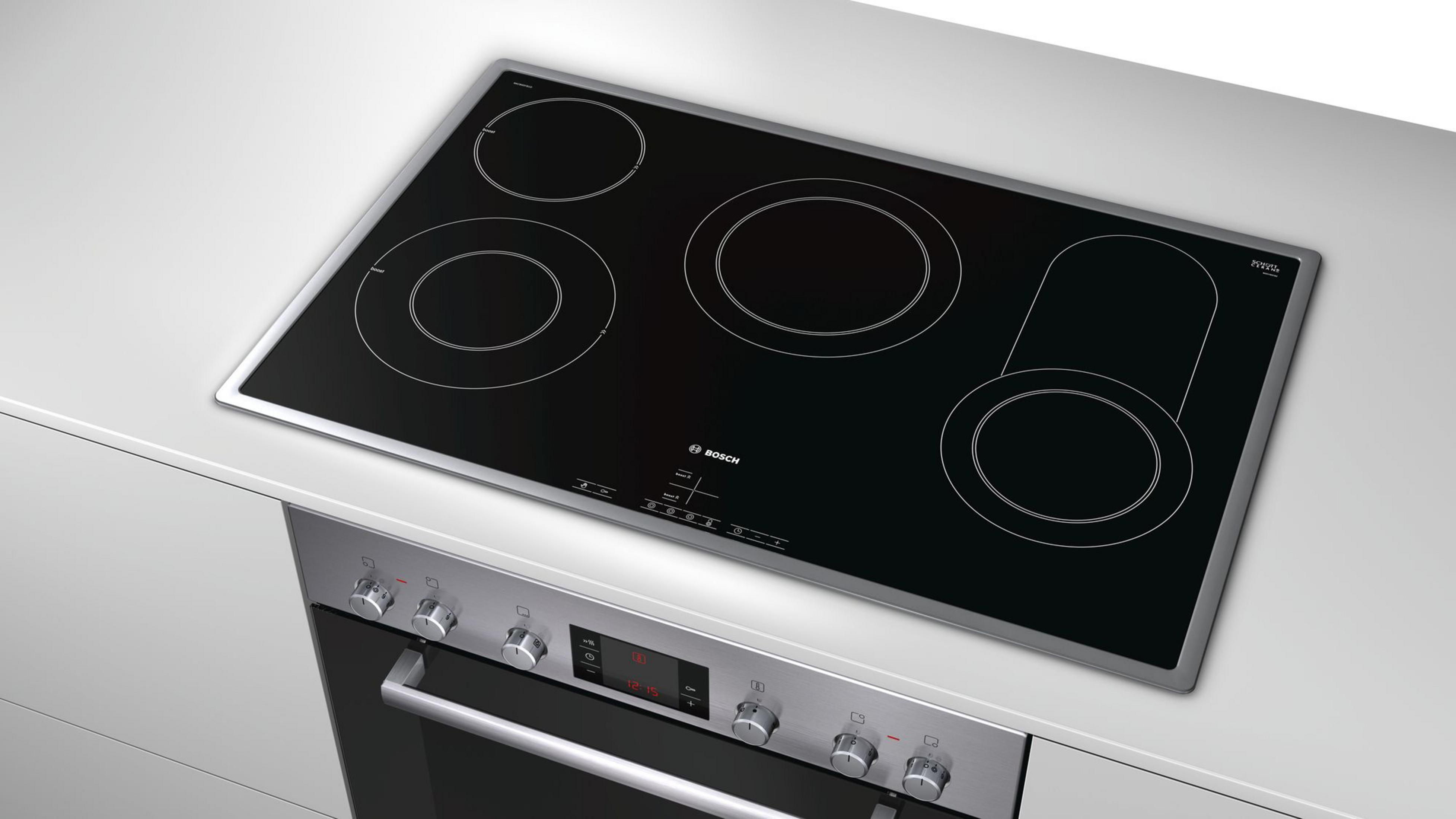 Induktionskochfeld mit vier Kochzonen und darunter ein Edelstahlbackofen, weißer Hintergrund.