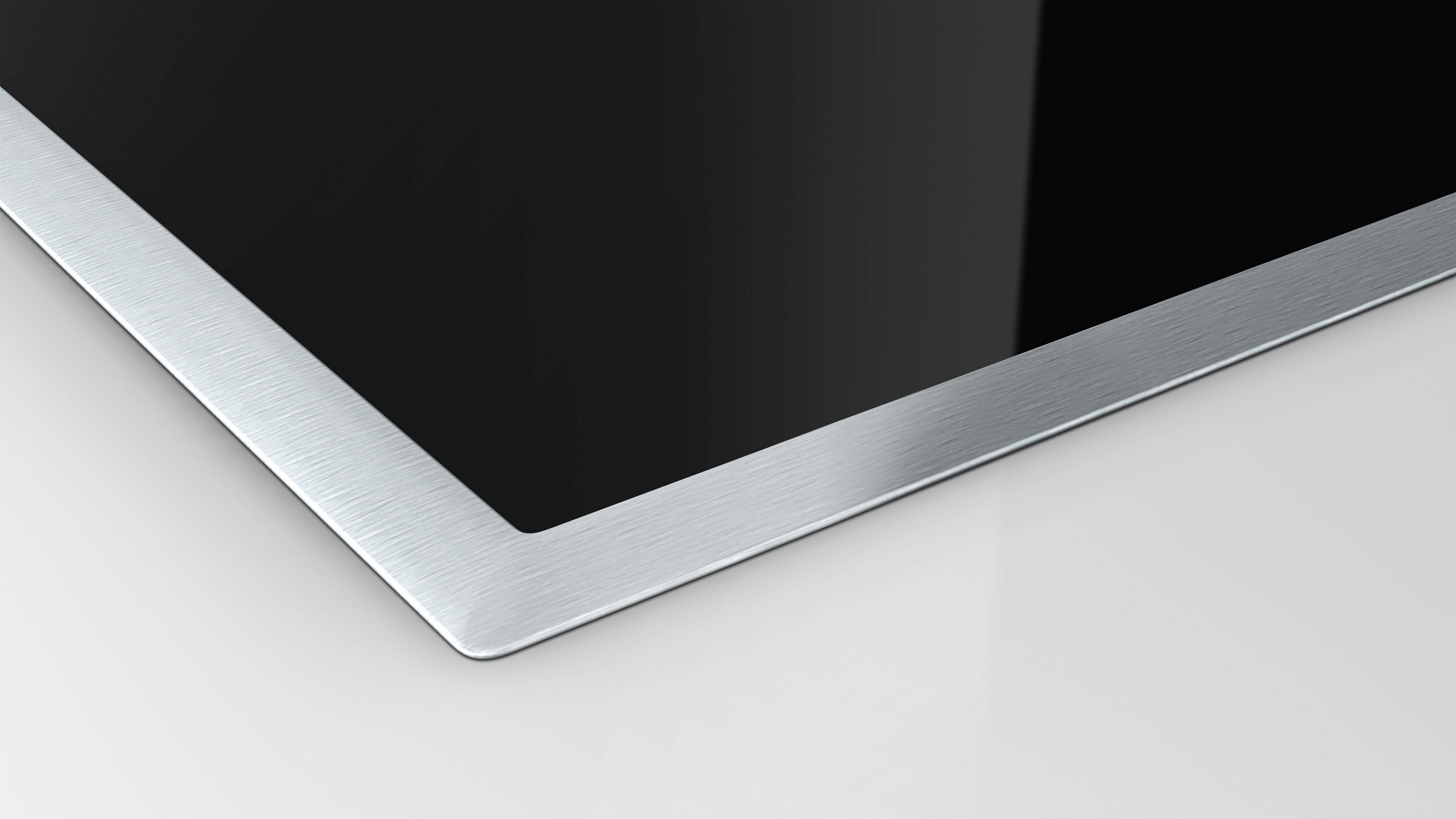 Zbliżenie czarnej płyty grzewczej ze srebrną ramką. Powierzchnia jest błyszcząca.