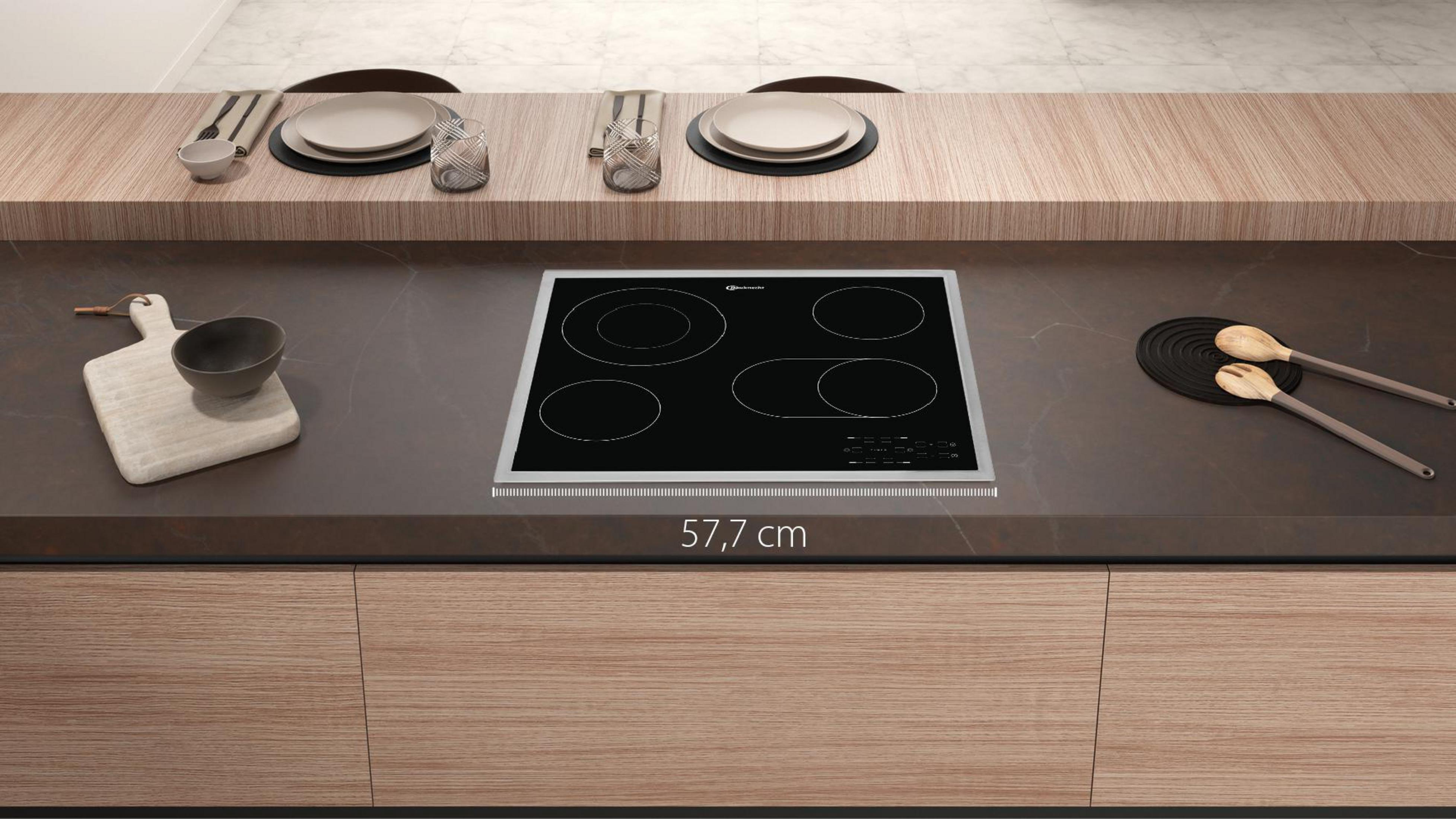 Piano di lavoro della cucina con piano cottura elettrico. Armadietti in legno sotto, piatti e decorazioni sul piano.