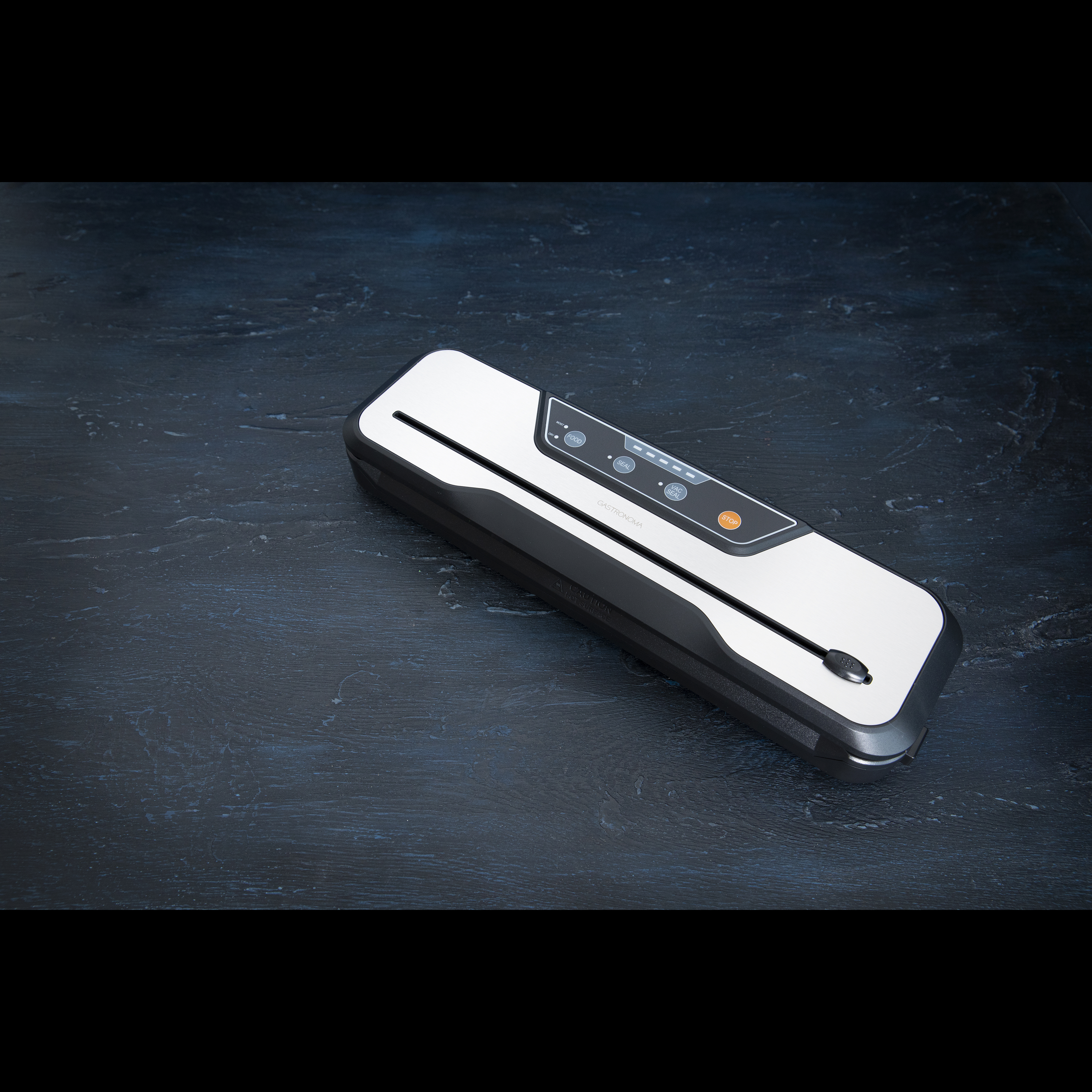 Zgrzewarka próżniowa na ciemnoniebieskiej drewnianej powierzchni.