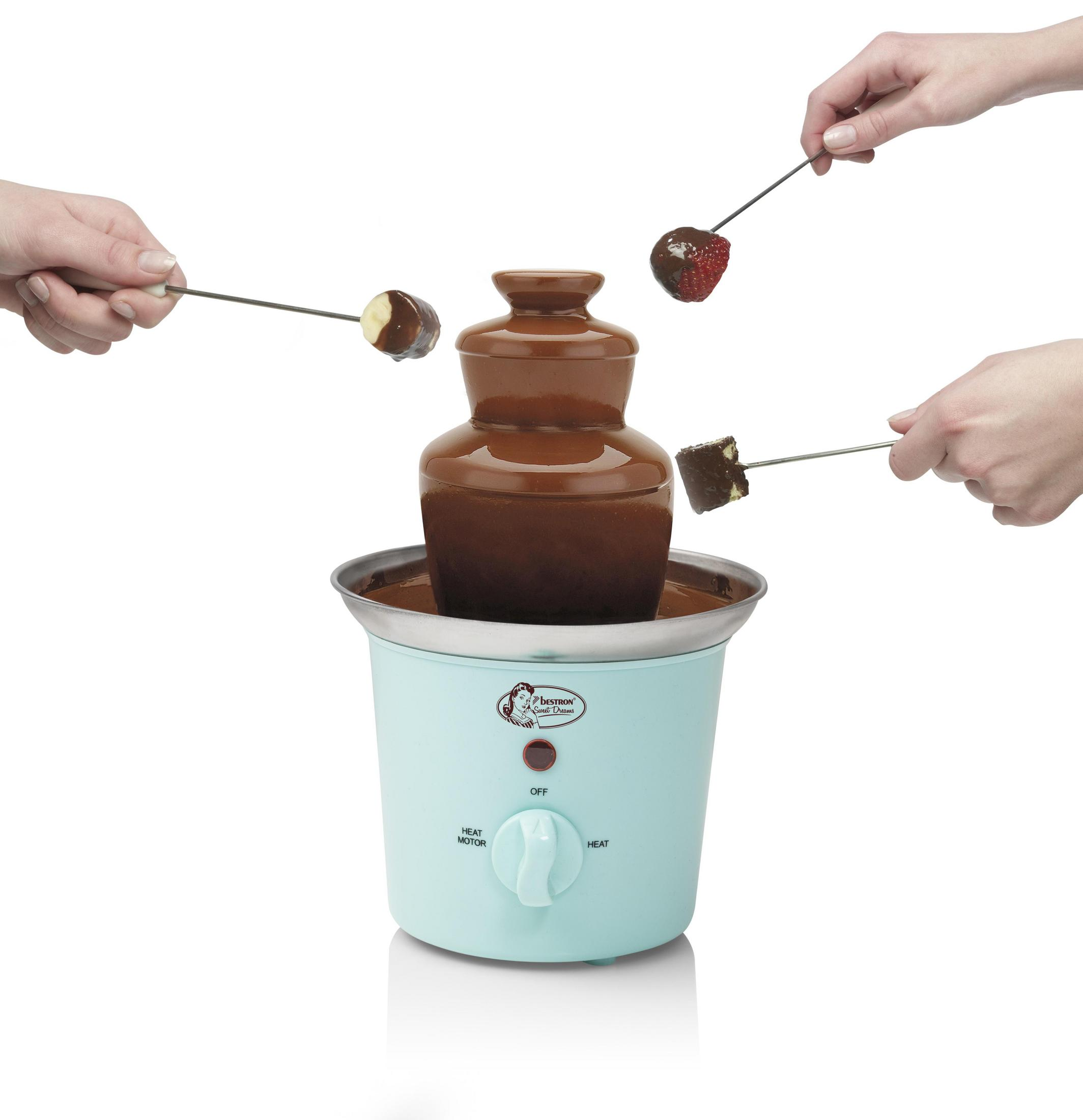 Fontana di cioccolato con frutta e mani che la immergono.