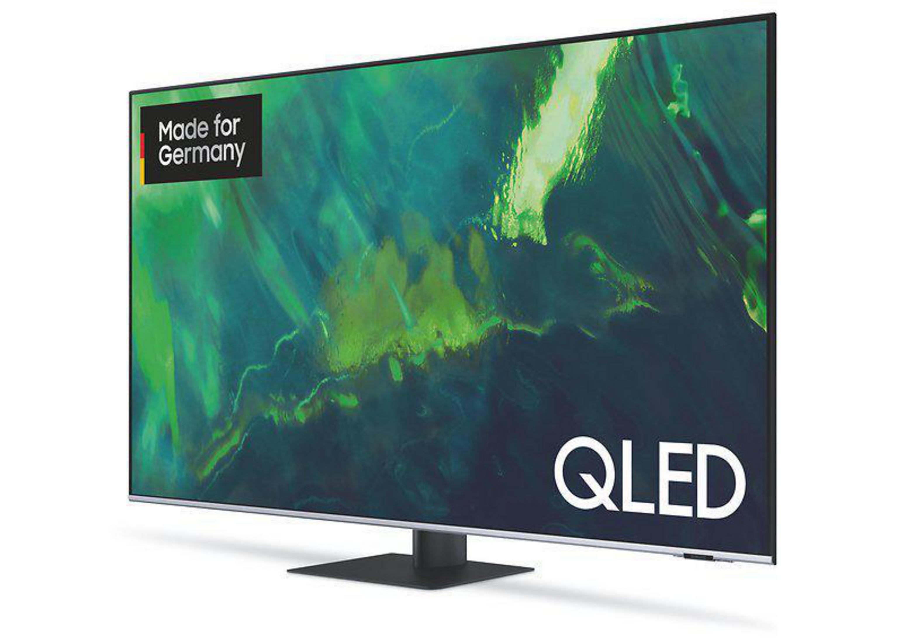 Telewizor QLED z białą ramką wyświetlający zielono-czarną sztukę abstrakcyjną. Widoczny jest tekst 'Made for Germany'.