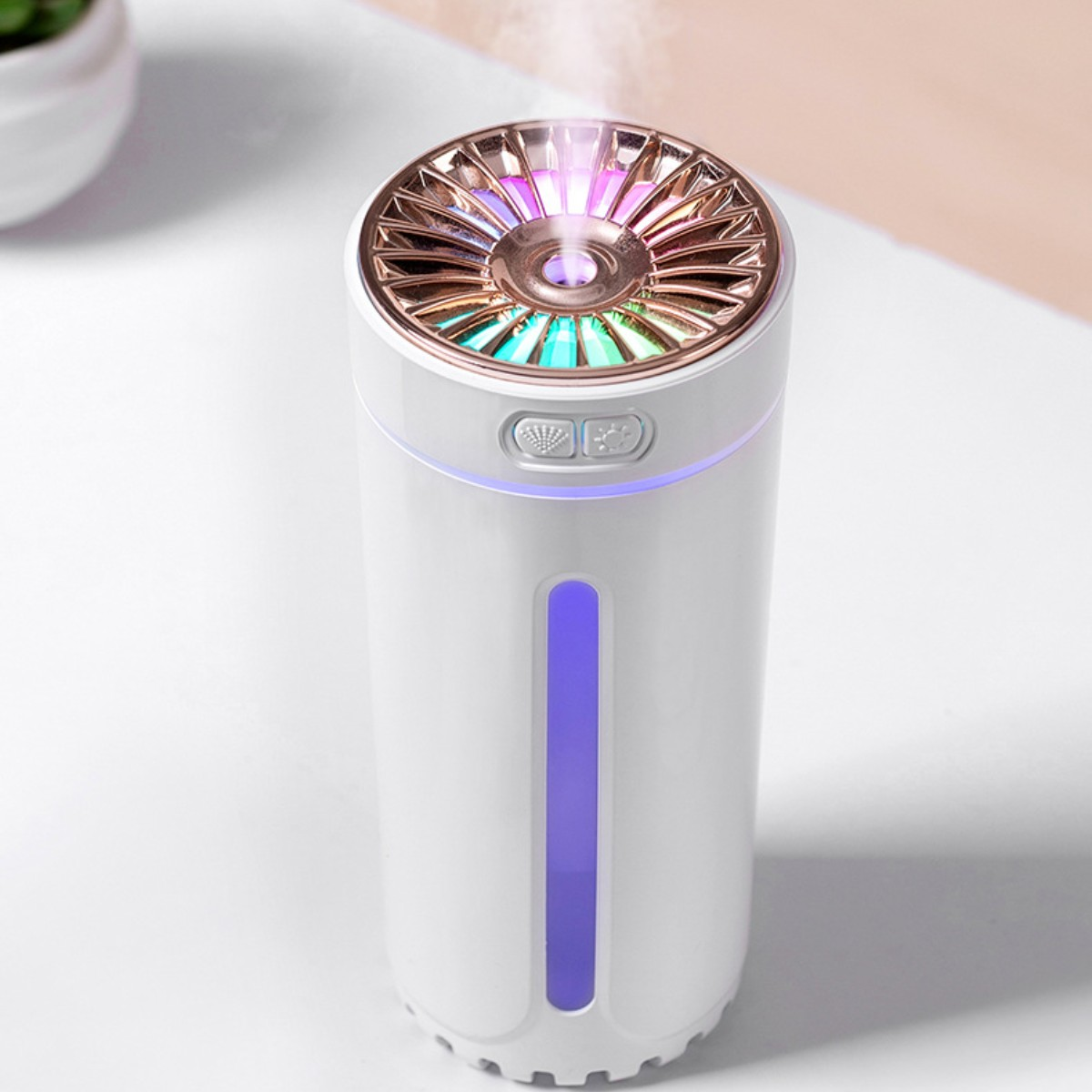 Humidificador blanco con parte superior dorada y luces de colores. Está sobre una superficie blanca.