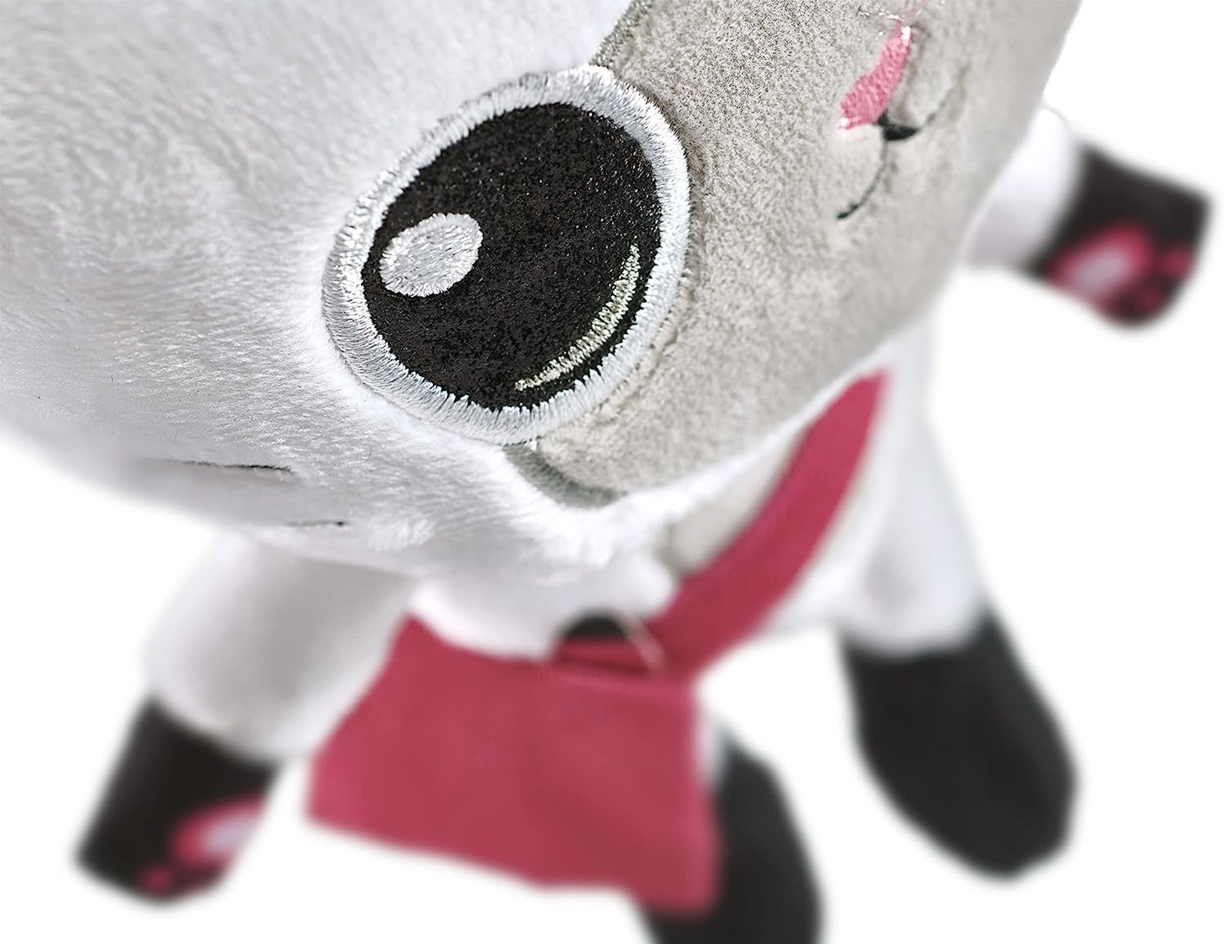 Pluszowa zabawka w postaci jagnięcia z czerwoną fartuchem, widok z bliska.