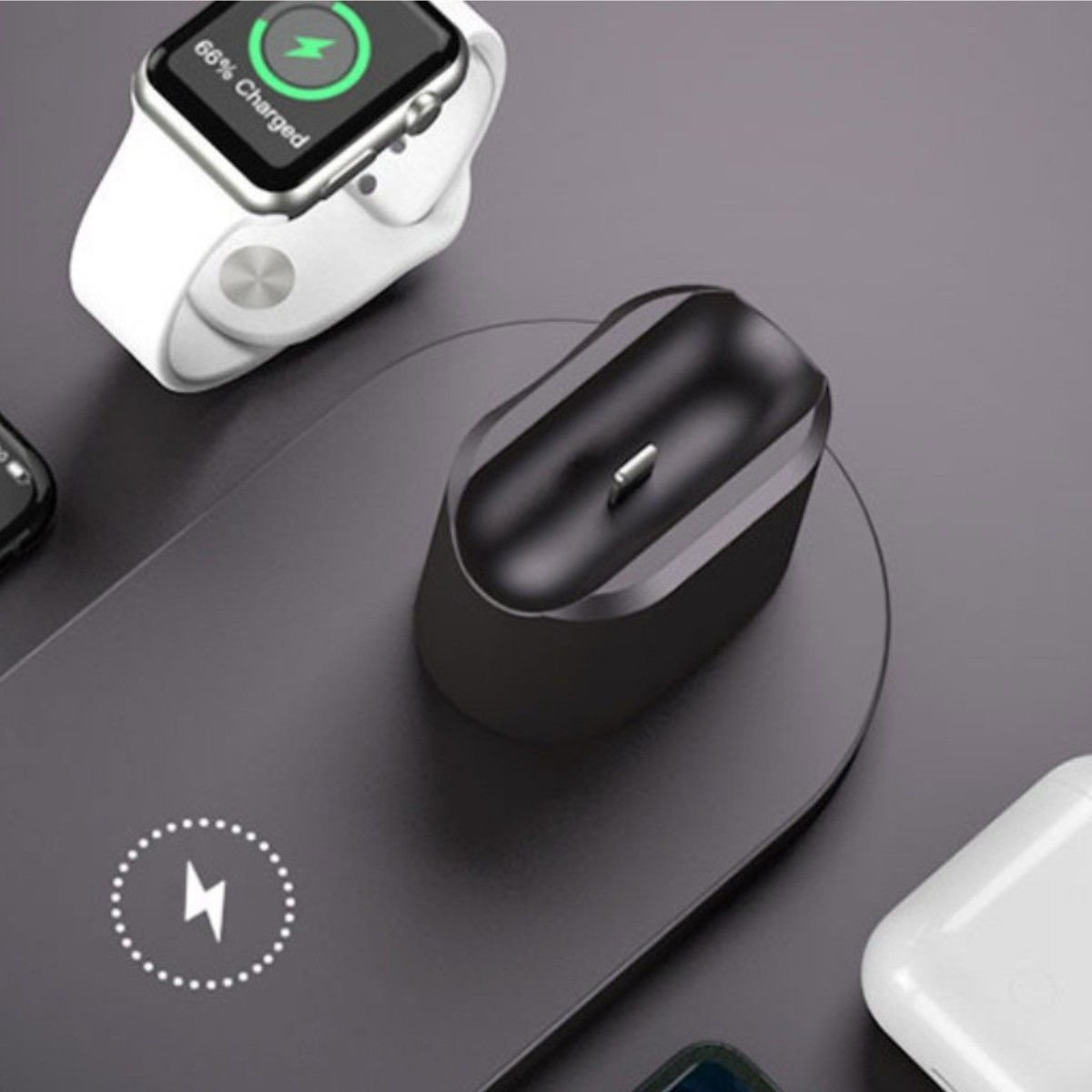 Eine Ladestation mit einer Uhr, AirPods und einem Telefon, das geladen wird. Dunkle Oberfläche.