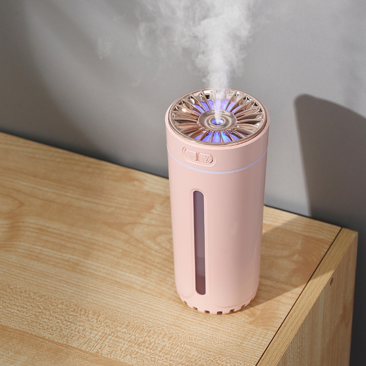 Un humidificador rosa y oro rosa sobre una mesa de madera. Tiene un indicador de nivel de agua y una luz.