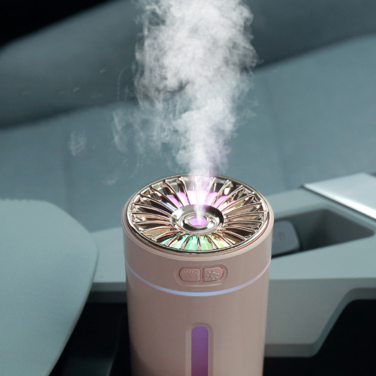 Humidificador de coche rosa con parte superior multicolor, emitiendo vapor blanco. Contra interior borroso.