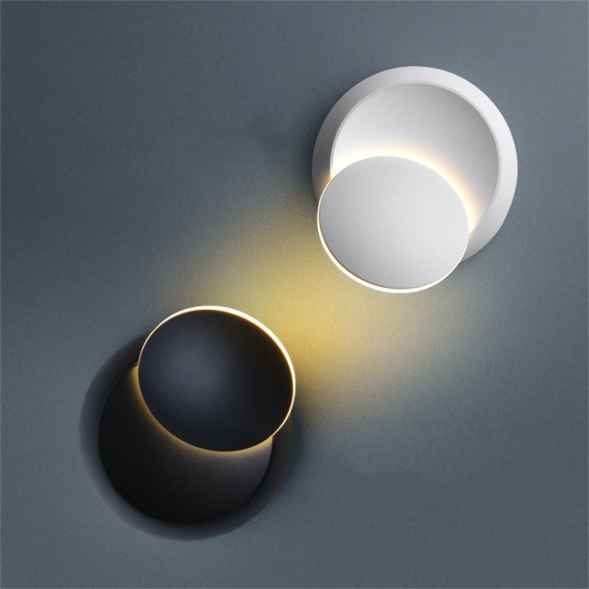 Zwei moderne Wandlampen, eine weiße und eine schwarze, strahlen warmes Licht aus.