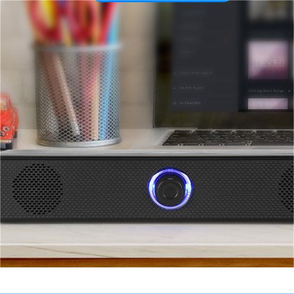 Eine Soundbar mit Lautsprechern und einem blau beleuchteten Bedienfeld auf einem Tisch.
