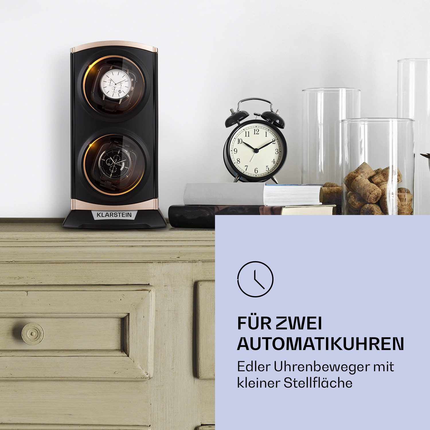 Ein Holztisch mit einer Uhr und einem Uhrenbeweger. Zwei Uhren befinden sich im Beweger, eine Uhr obenauf.