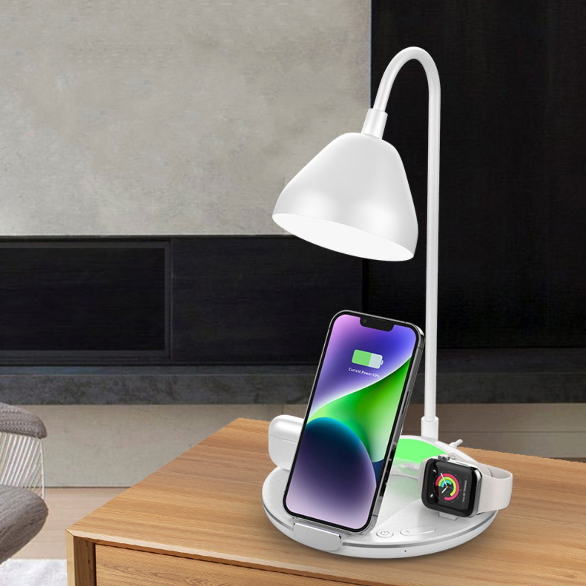 Lámpara blanca con teléfono, reloj y plataforma de carga en una mesa de madera. El teléfono muestra la carga.