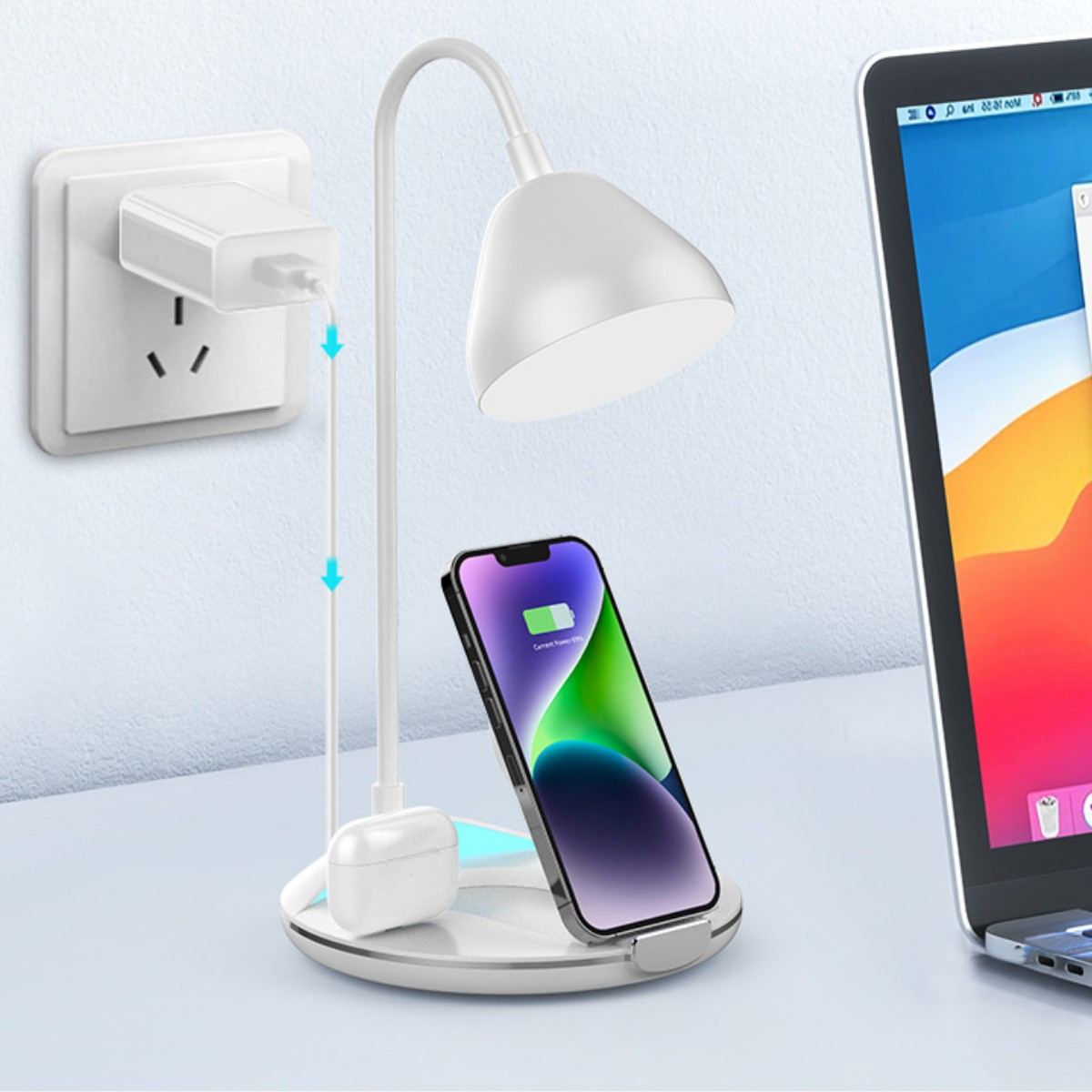 Una lámpara de escritorio con un teléfono cargando y un portátil.