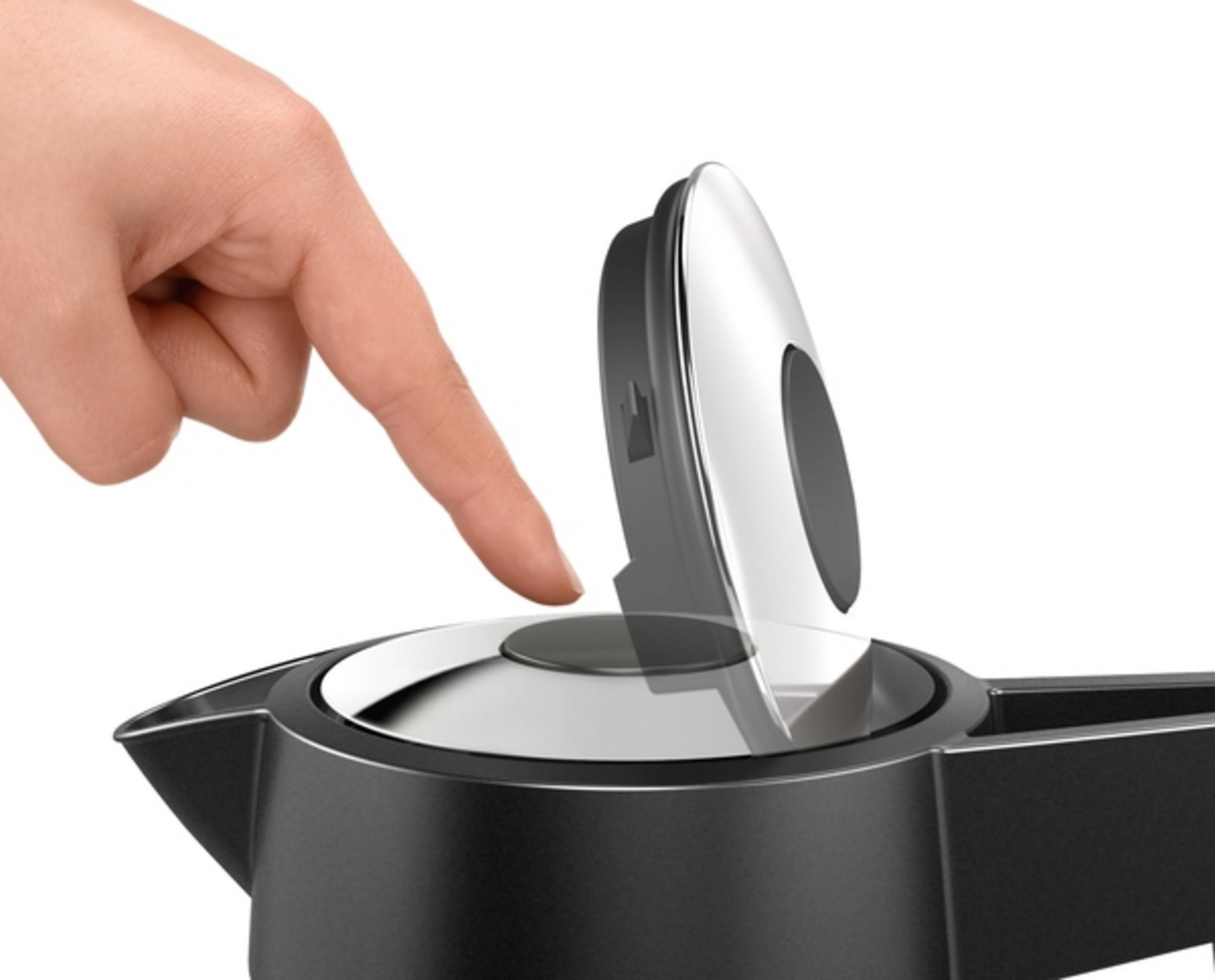 Ręka naciska czarny przycisk na czarnej i srebrnej pokrywce czajnika.