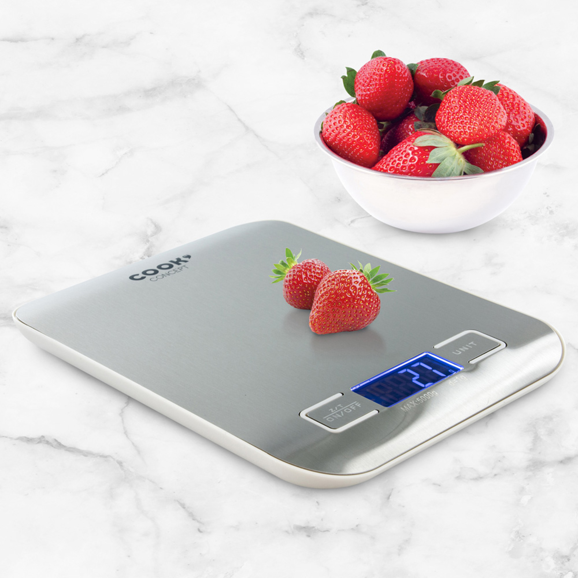 Báscula de cocina digital con fresas. Balanza plateada con un cuenco de fresas rojas sobre superficie de mármol.