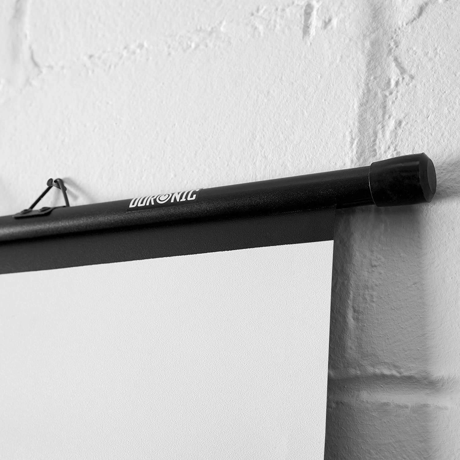 Eine schwarze Projektionsleinwand ist an einer weißen Ziegelmauer mit einer schwarzen Stange befestigt.